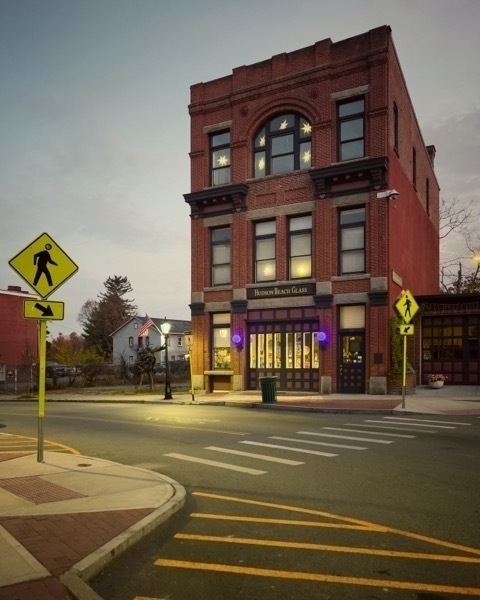 Three story commercial brick building with street crossing in front of it.