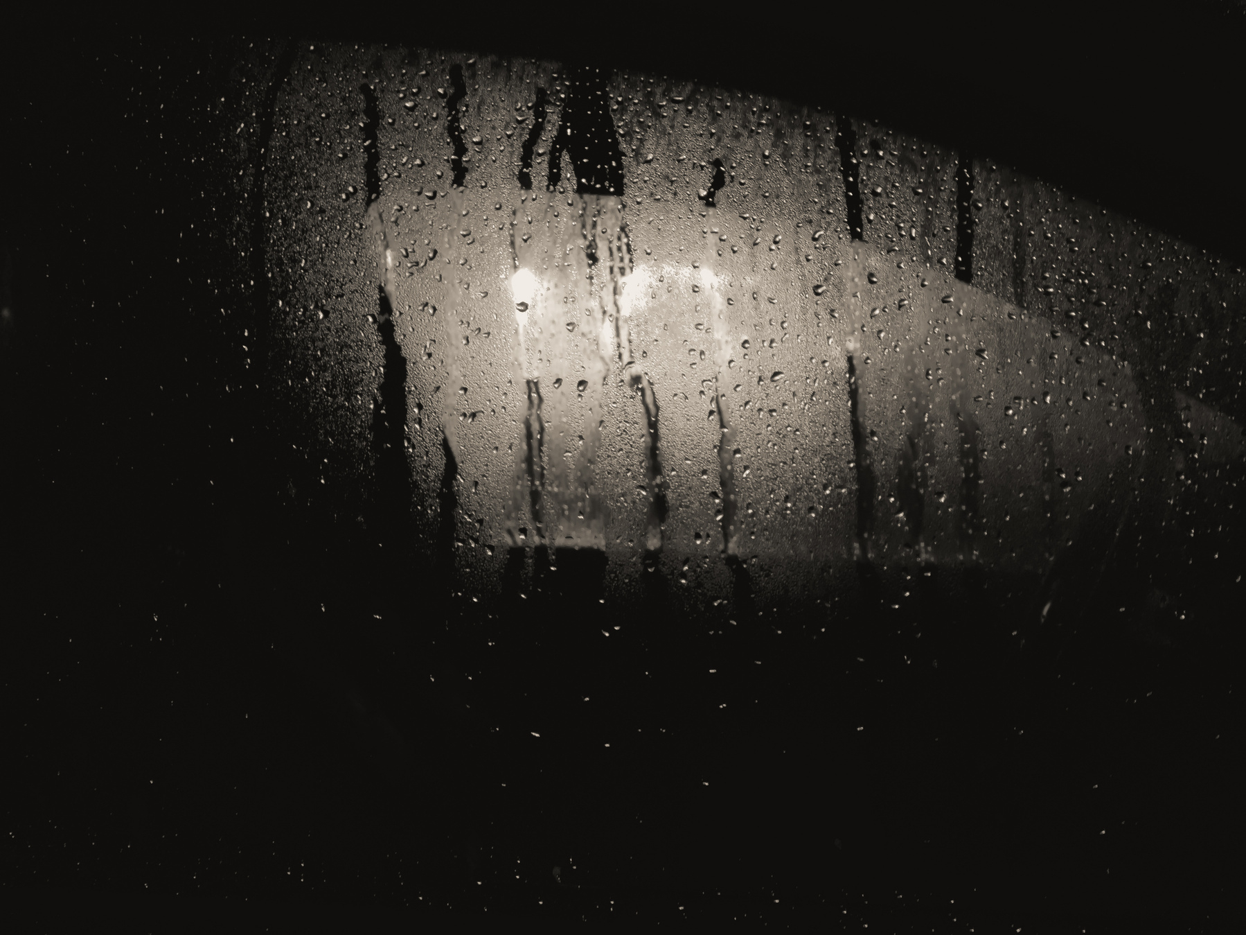 Street lights through car window covered with dew and raindrops.