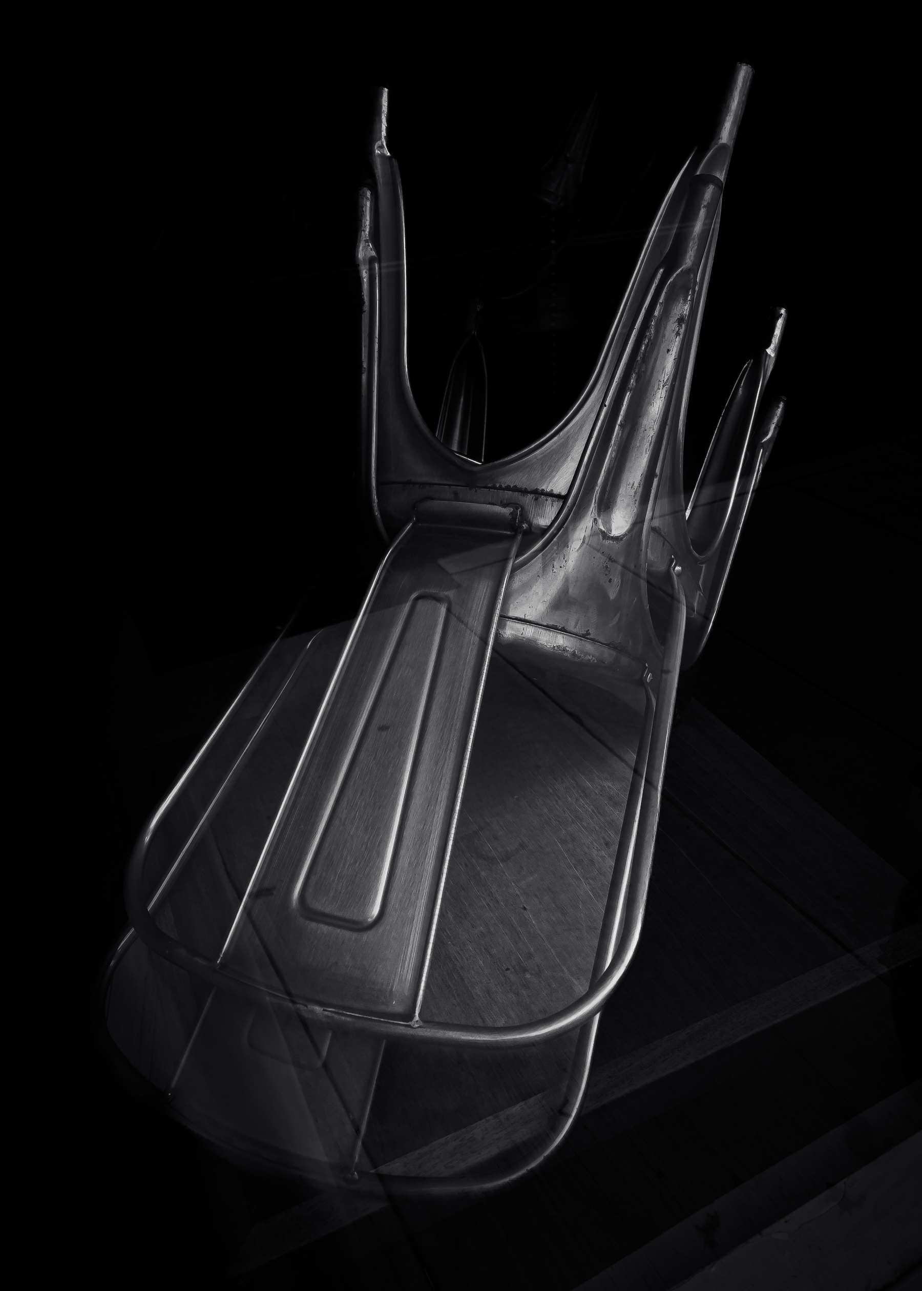 two chairs inverted on a table in darkness 