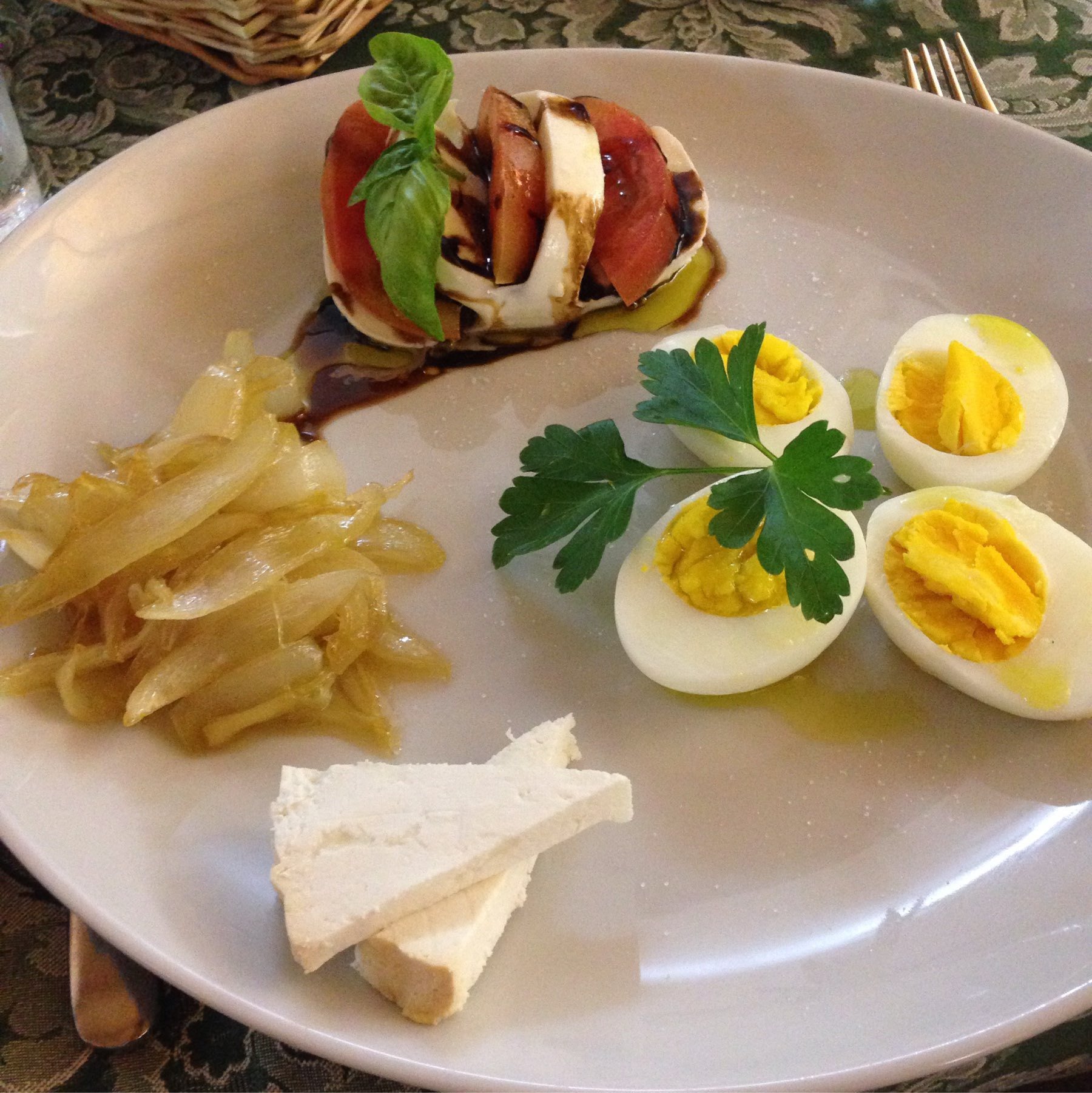 dinner plate with caprese salad, onions, and eggs