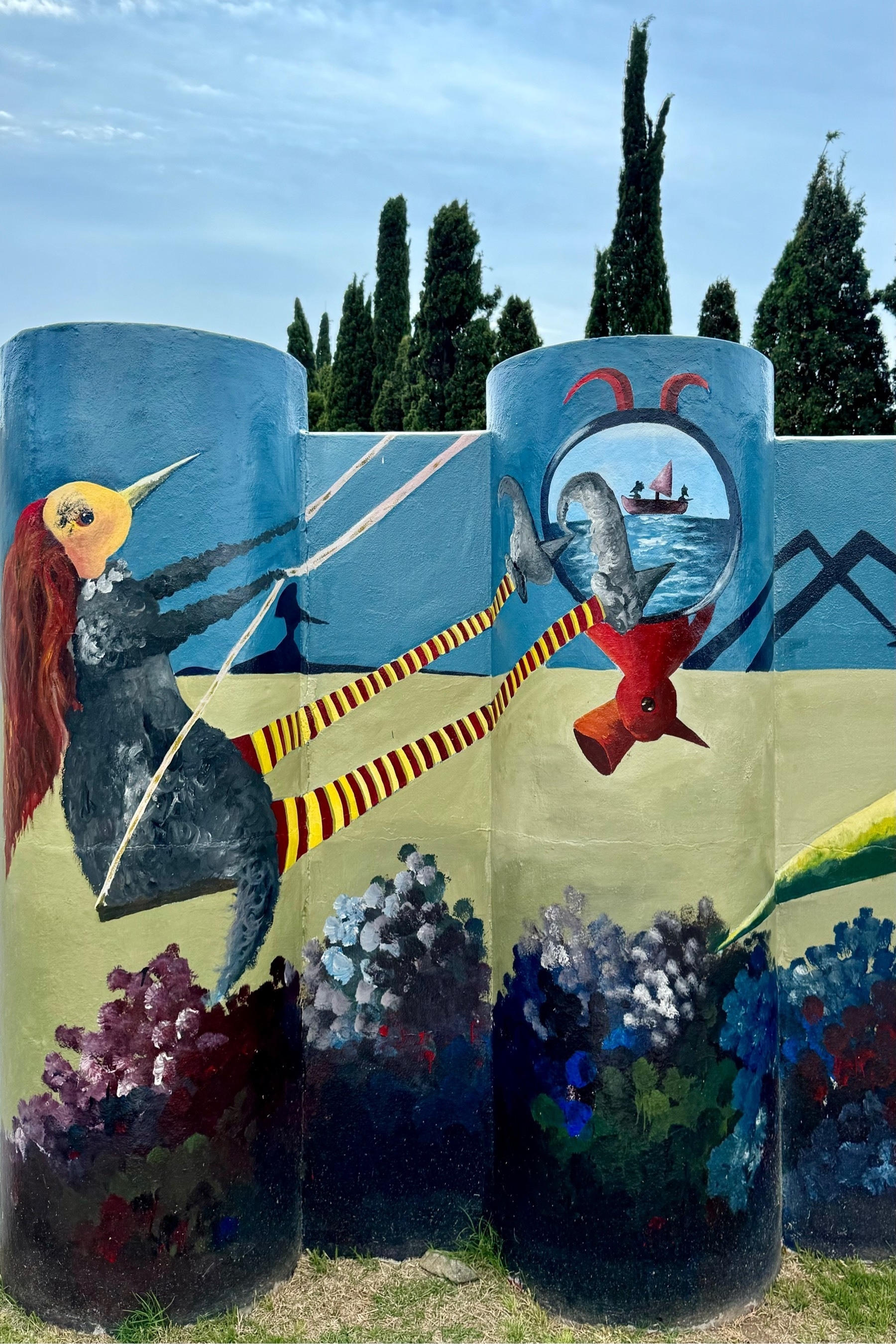 Wall mural of a bird-girl with long red hair, swinging on a swing, with a sailing boat off in the distance