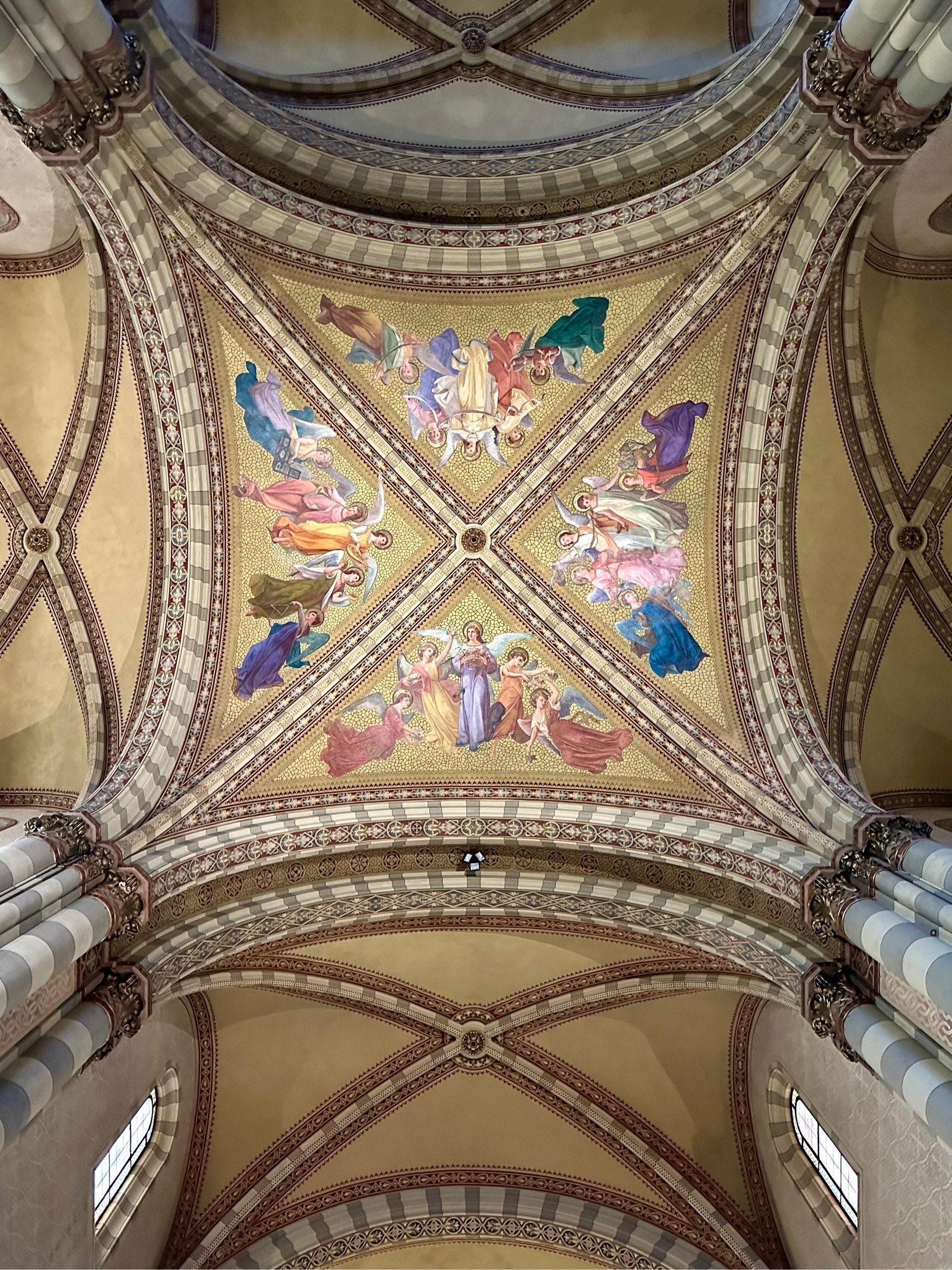 Looking up at a vaulted ceiling fresco, split into four quadrants each containing five figures