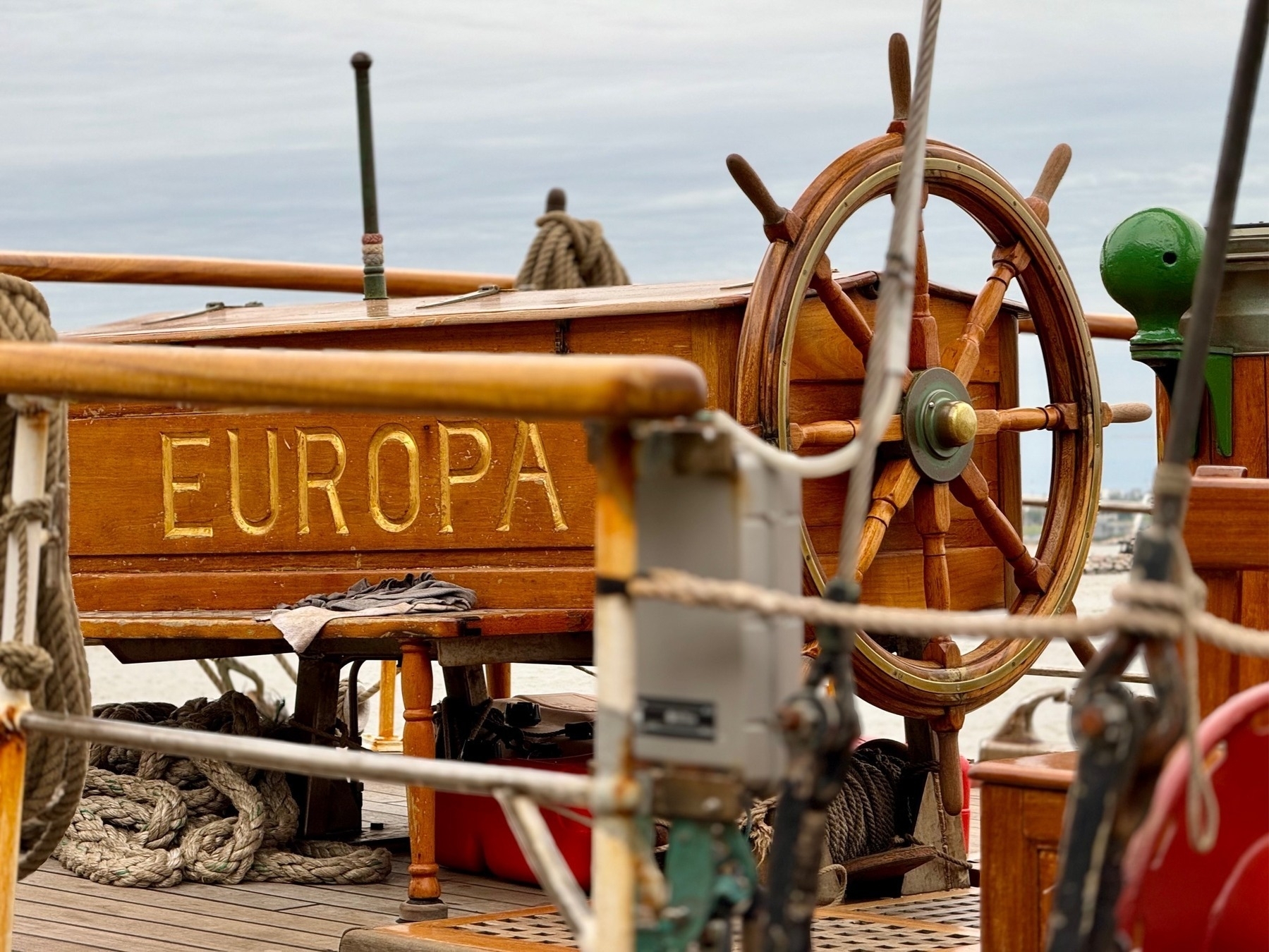 The stern of a sailing boat, including the wheel, with her name 