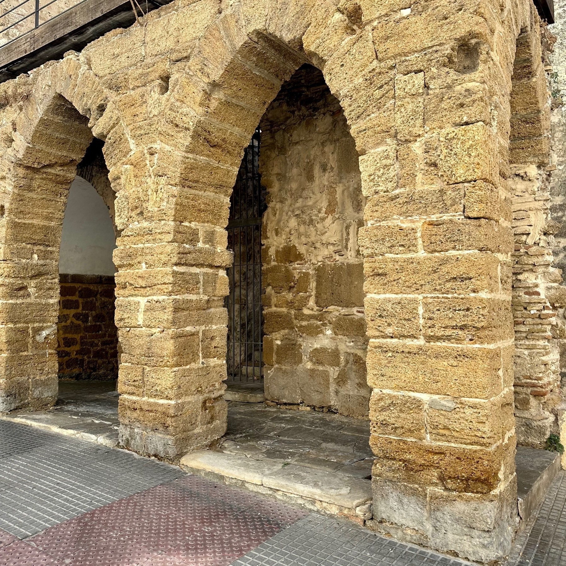 Three arches, pointed at the top, one at 90-degrees to the other two, and formed of yellow-coloured rough stone bricks