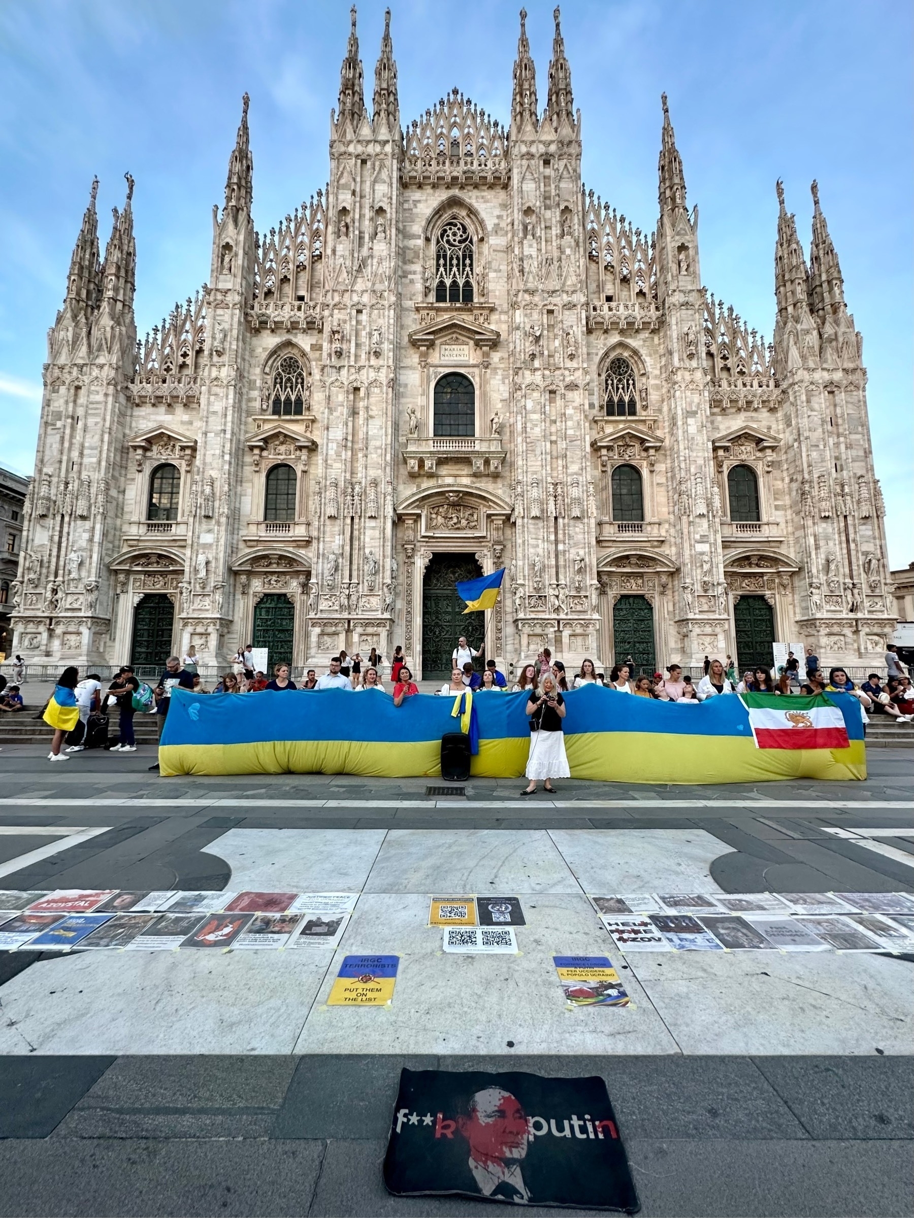Milan cathedral, against a blue sky, with a protest for Ukraine in front 