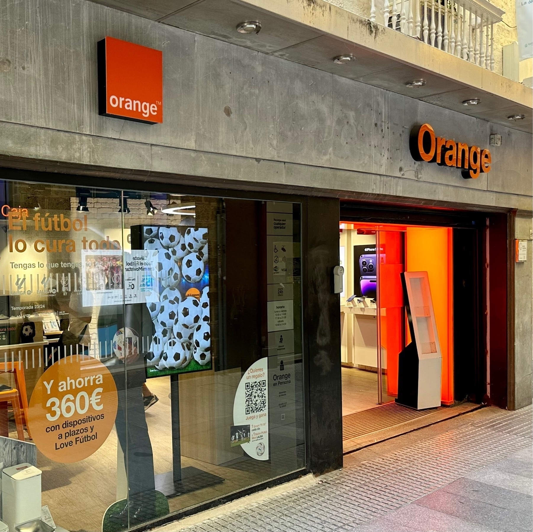 Grey frontage for the Orange (i.e. France Telecom) shop, with the square Orange logo and Spanish-language offers on the window