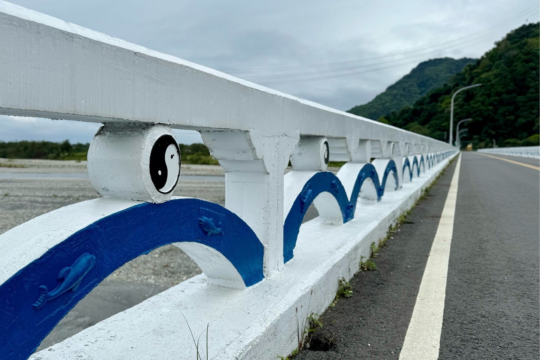 Looking across a white bridge, the lower part made up of blue arches, with embossed dolphins and the yin and yang symbol