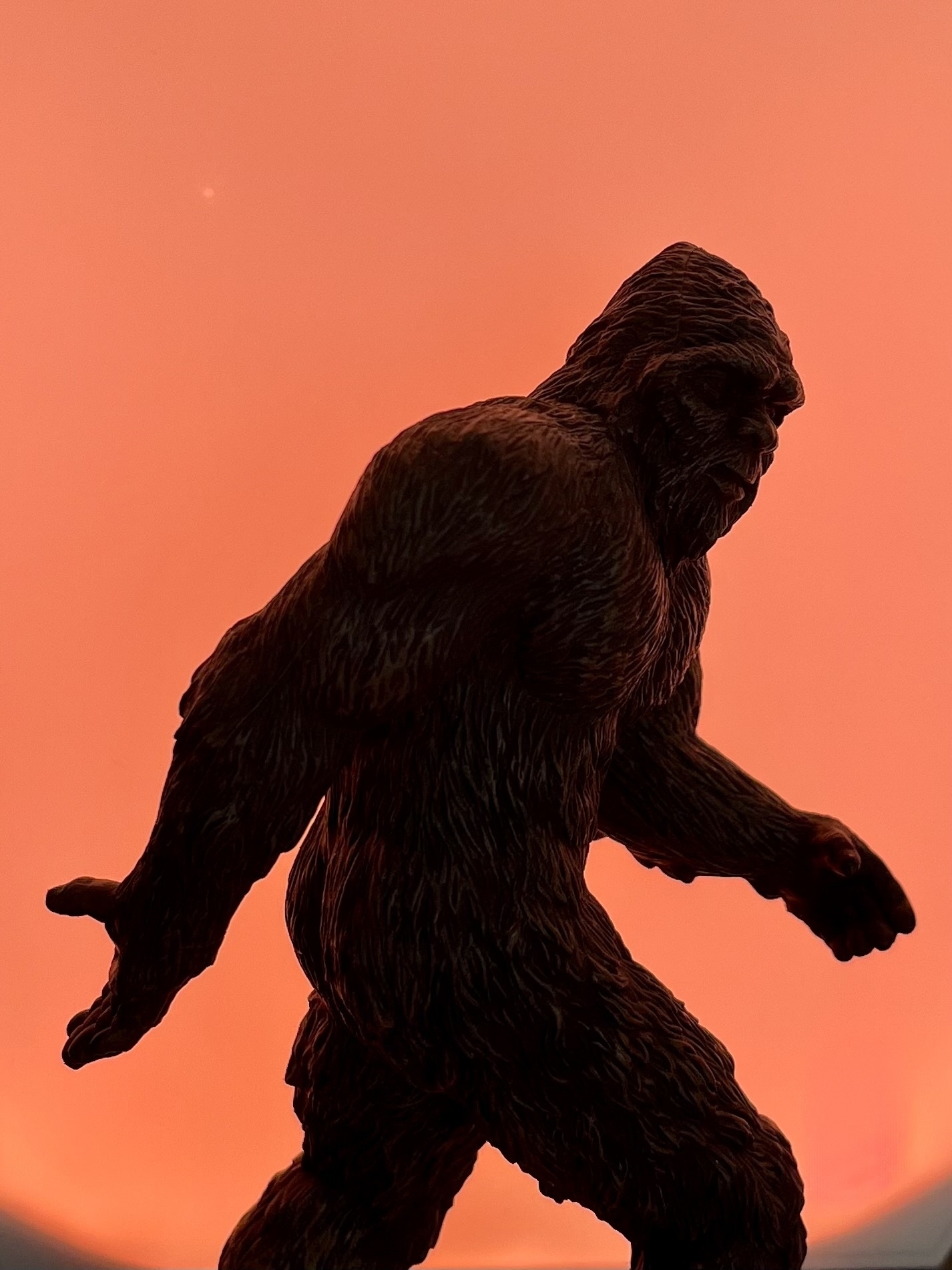 The silhouette of a Sasquatch against an orange background. 