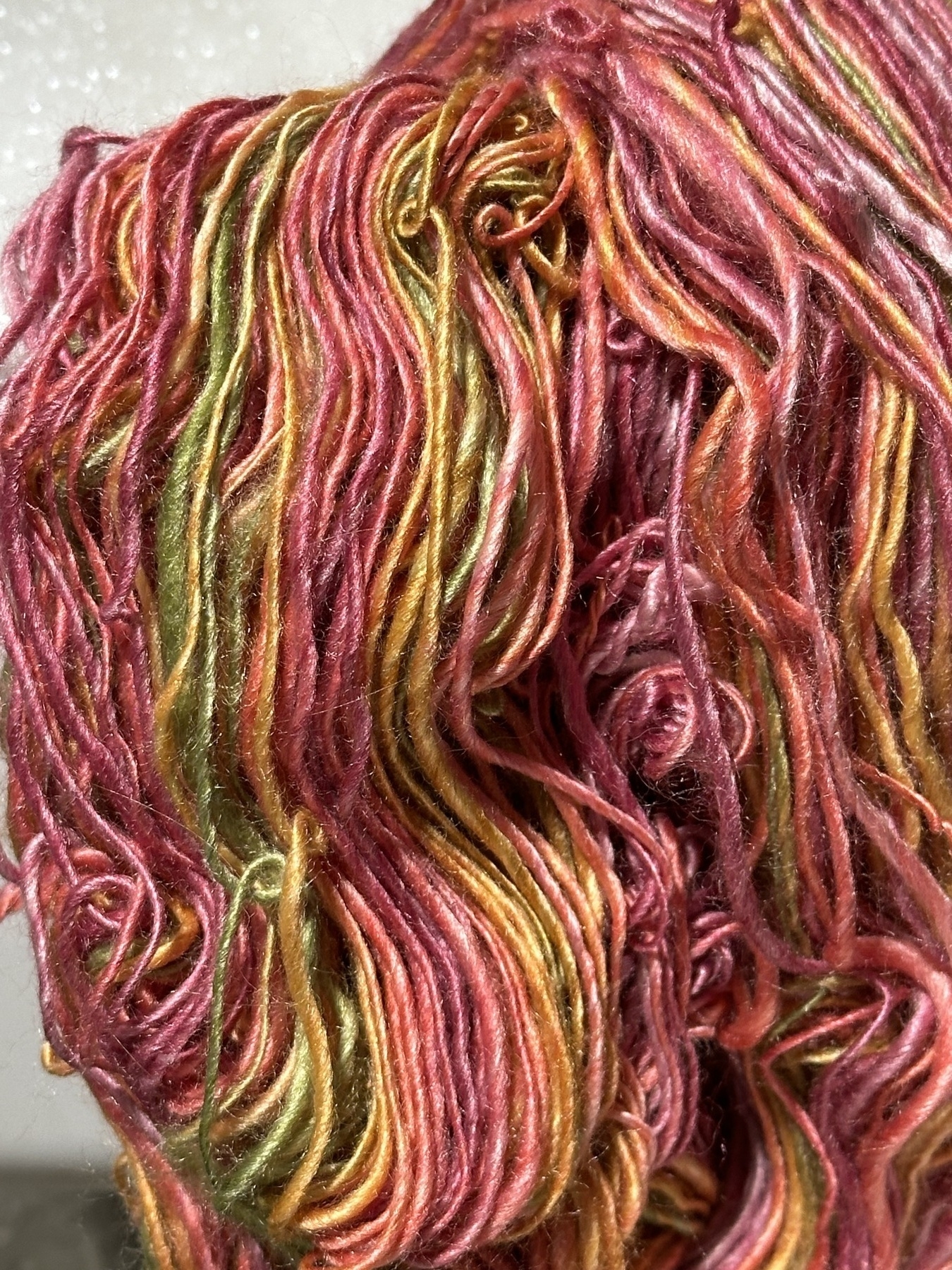 close up of silky looking pink, spring green, and yellow handspun yarn