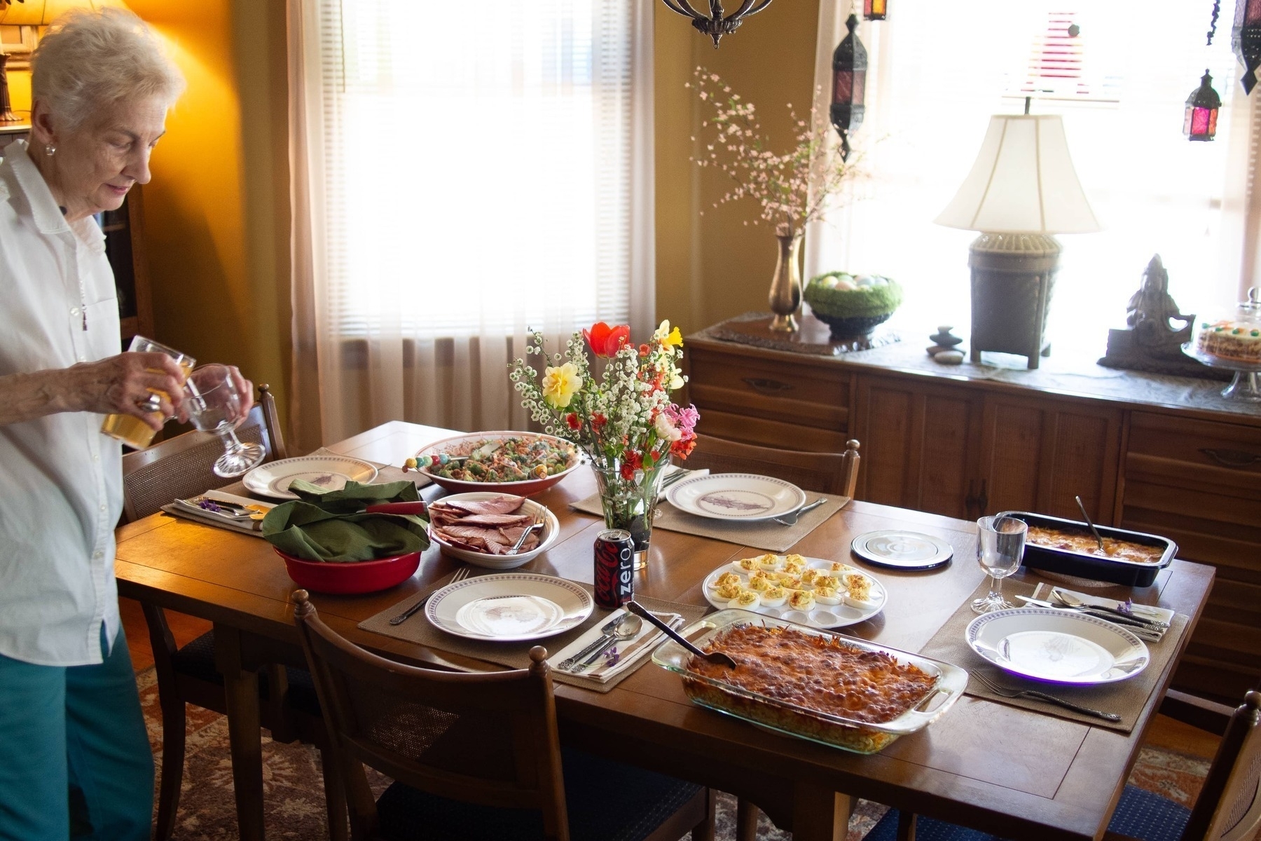 Person fills goblet by a table set with Easter meal - Olympus E-M5