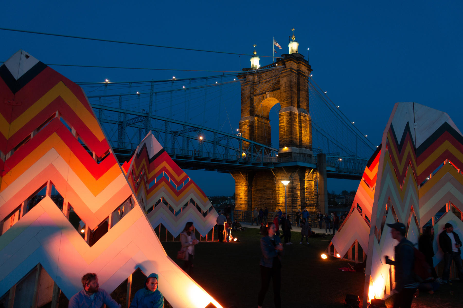 Colorful TeePee-like art installations in front of a bridge at night - Sony RX100