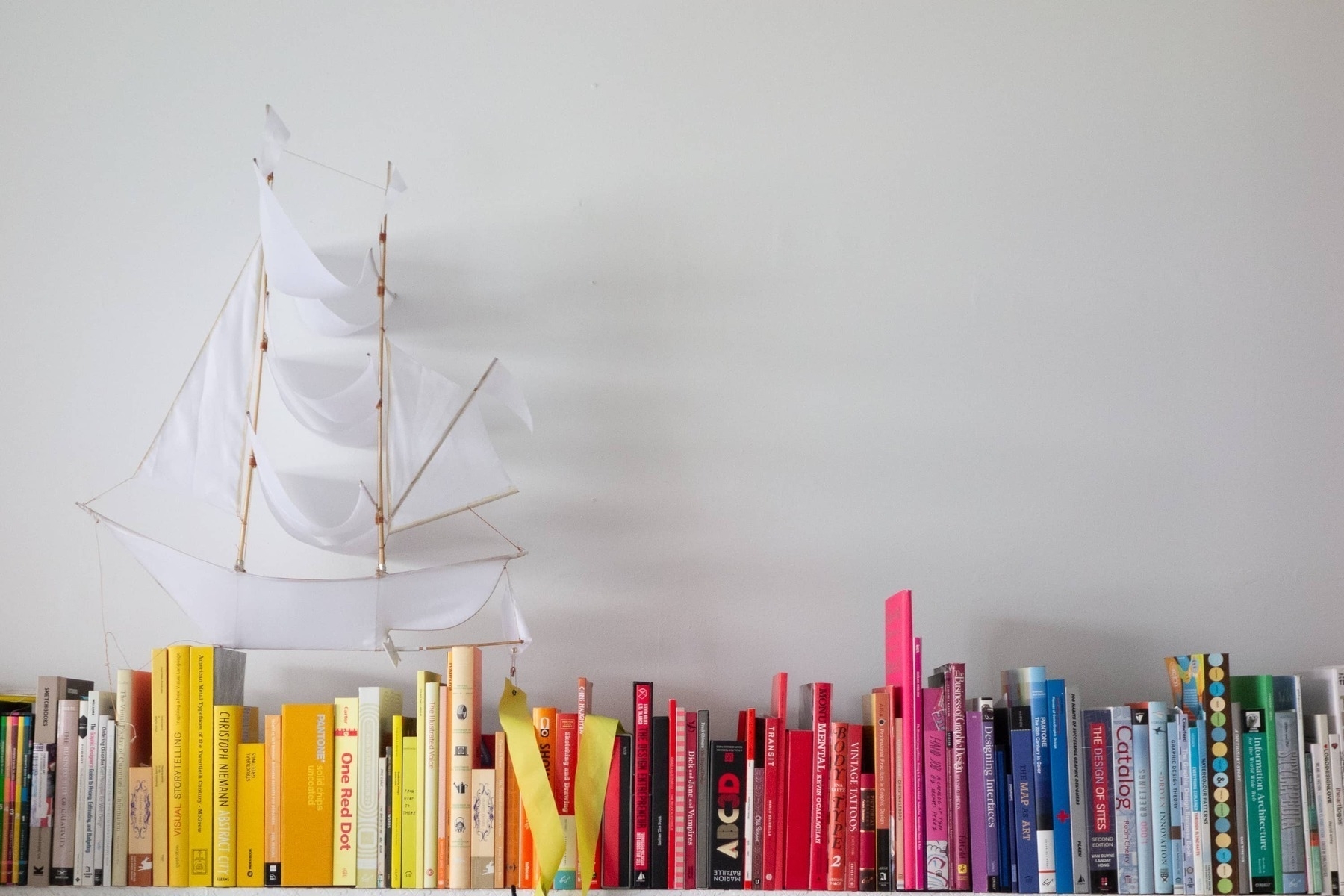 Books arranged by color with a sailing vessel - Sony RX100