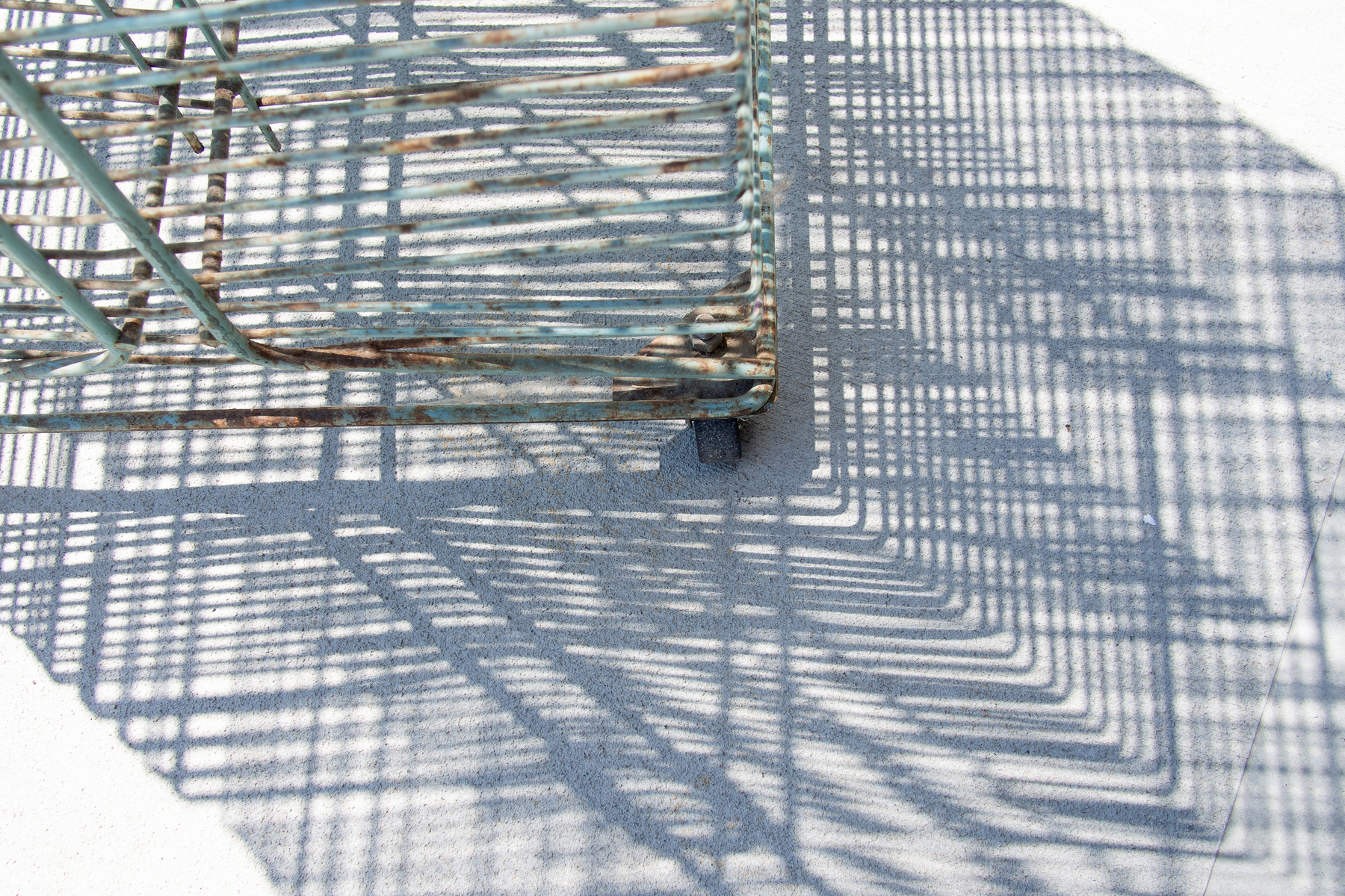 Wire drying rack for screen and letterpress prints casts shadow on concrete floor. - Olympus E-M5