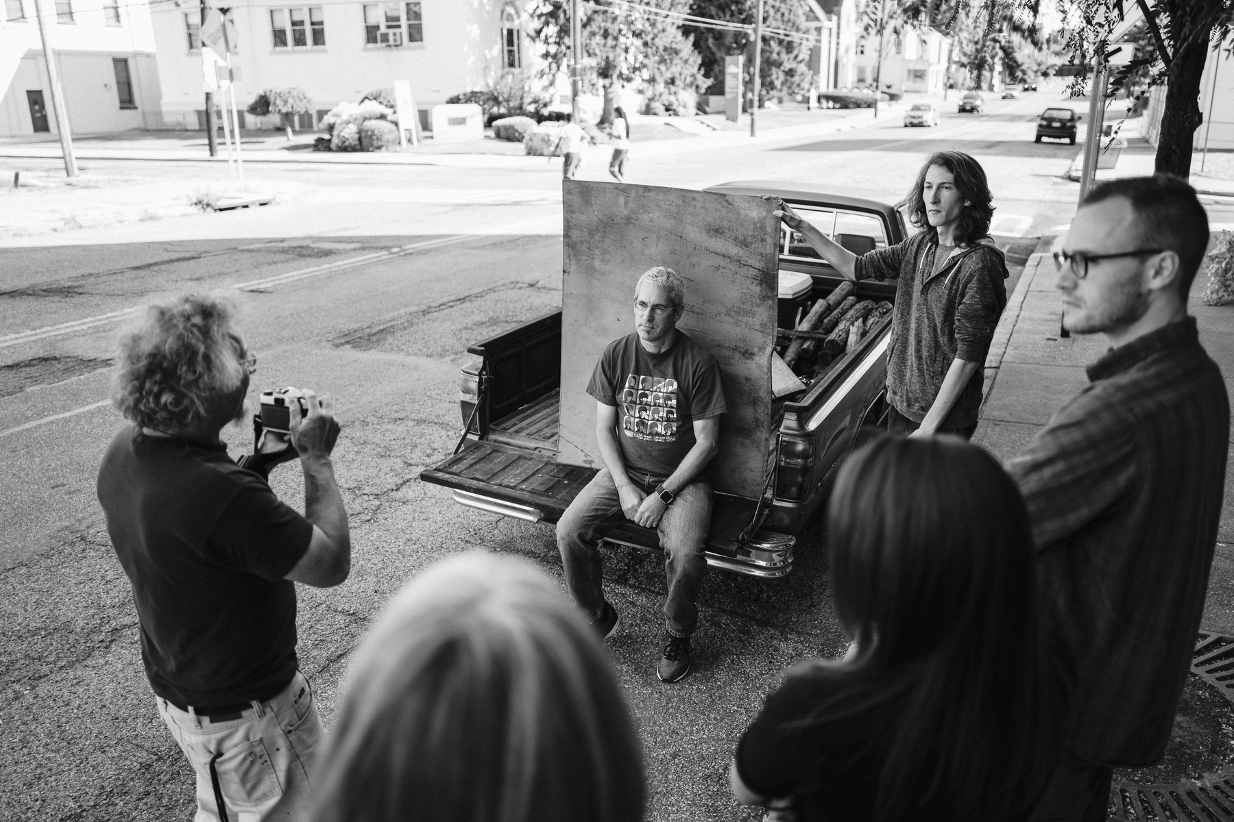 Man holds up a plywood backdrop for a portrait session in the back of a pickup - Leica Q