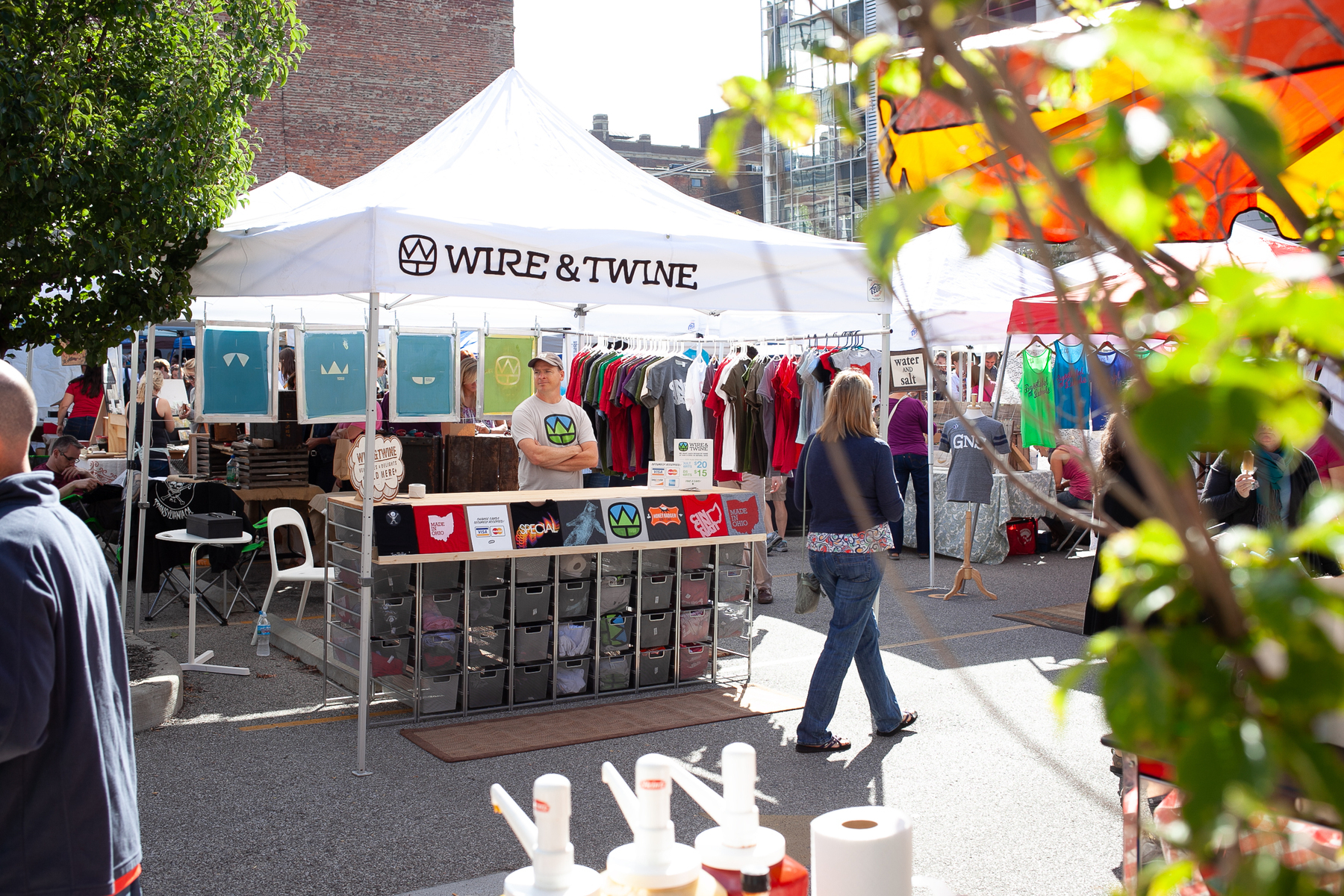 Tom stands behind the display of t-shirts at the Wire & Twine booth - Canon 5D Mark II