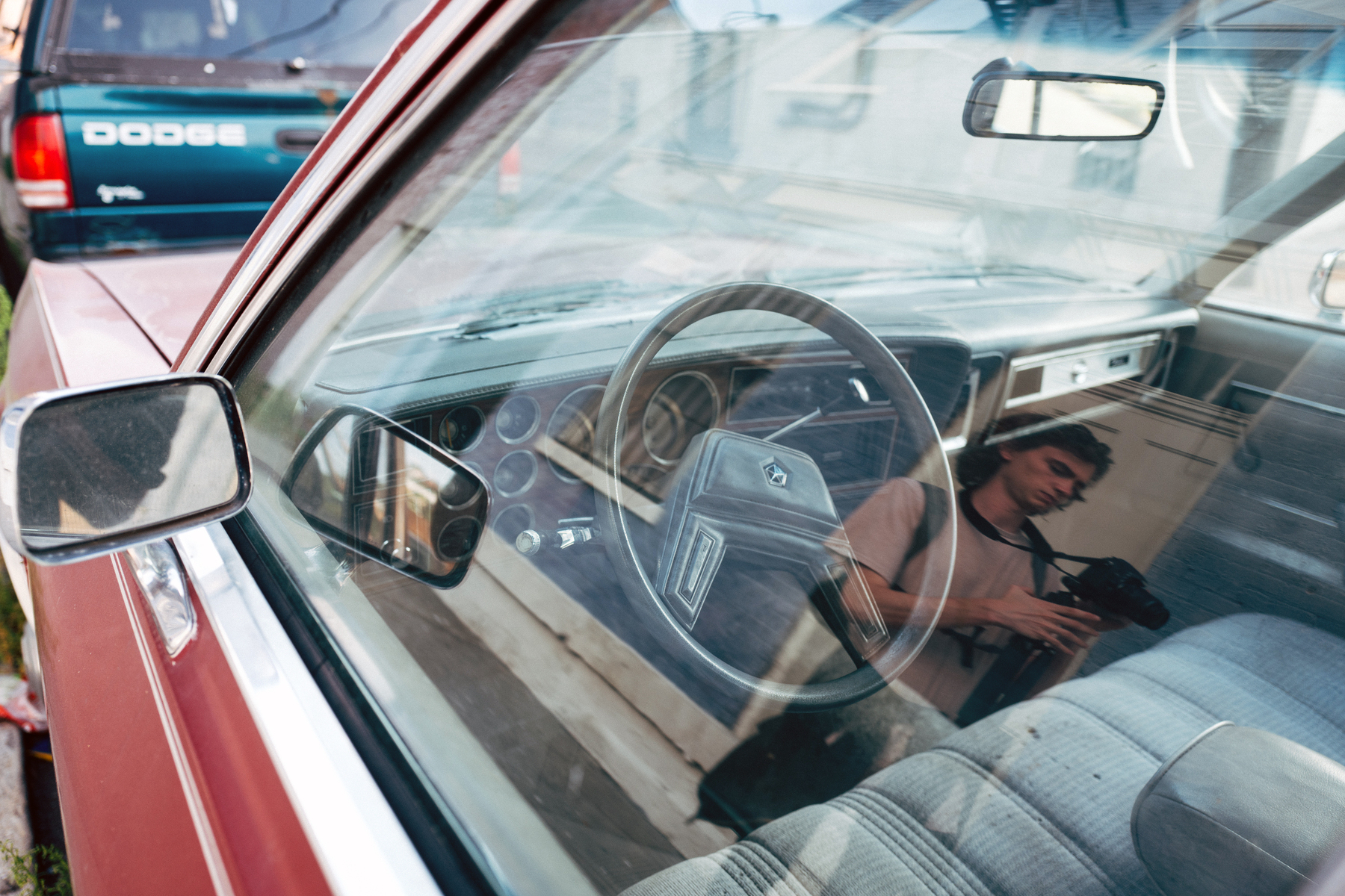 Reflection of person filming with digital camera in window of Dodge Diplomat - Leica Q