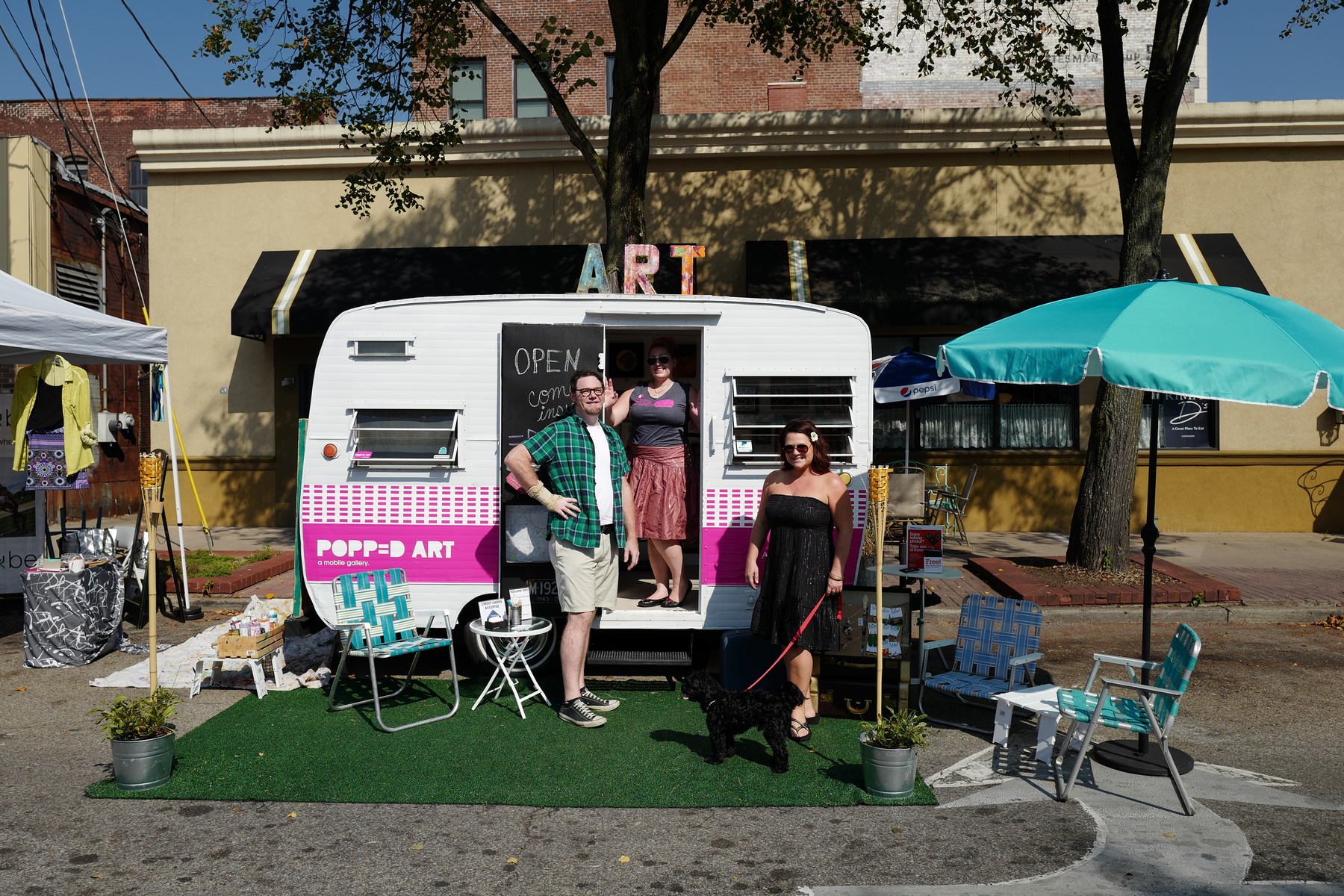 Three folks stand by a travel camper turned into art gallery - Leica Q