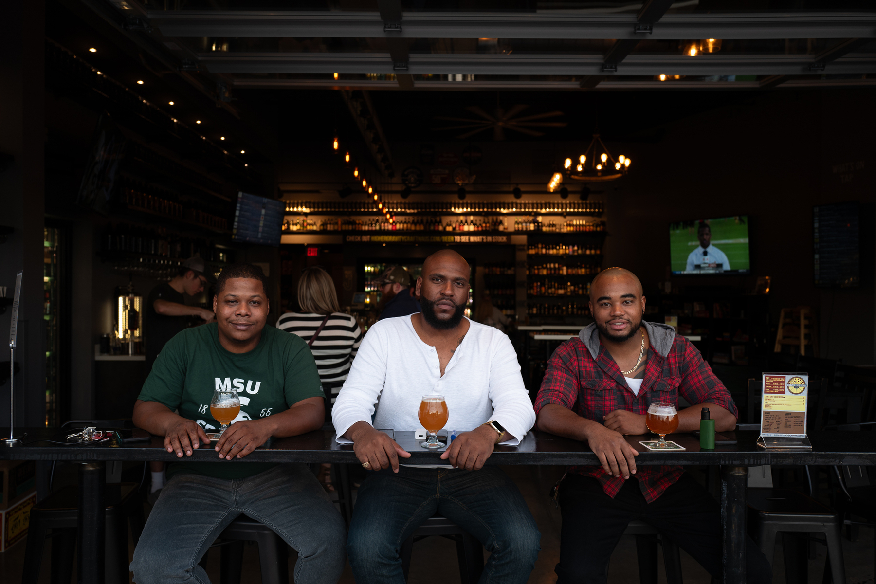 Three gentlemen sit at an outdoor bar with snifters of beer - Leica Q