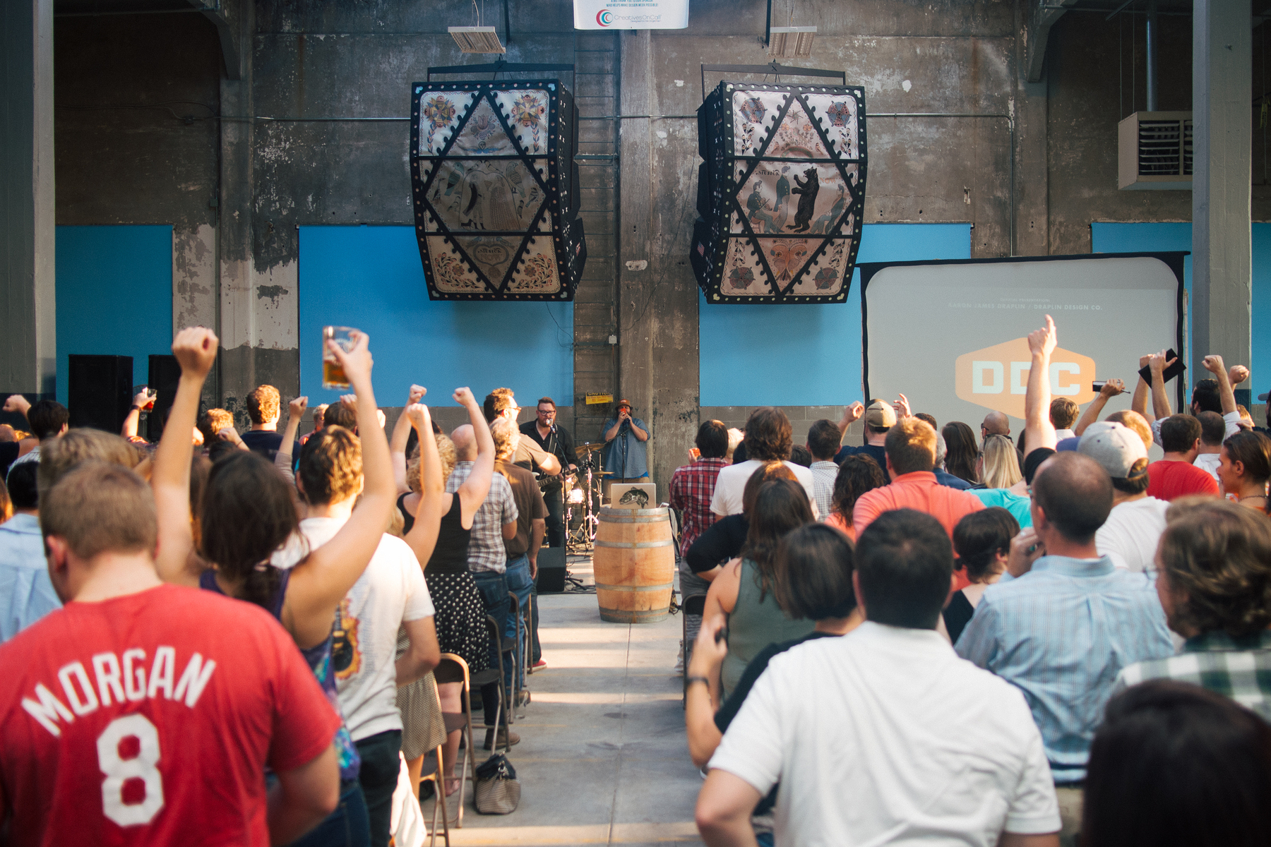 A crowd of folks with fists and beer in the air while Ohio Knife plays rock music at a brewery for a design conference with Aaron James Draplin speaking - Olympus E-M5