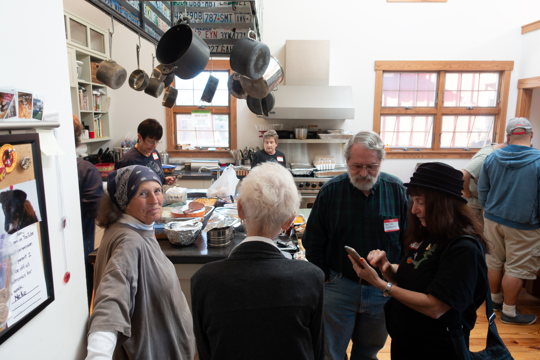 A busy kitchen filled with folks and potluck, Wendy's mom is in the left of the frame smiling at the camera - Sony RX100