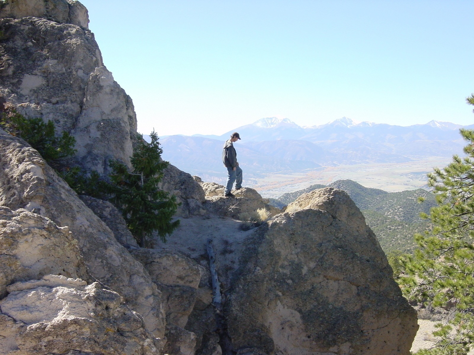 A man stands dangerously close to the edge of the side of a rocky cliff in Colorado - Sony Cybershot