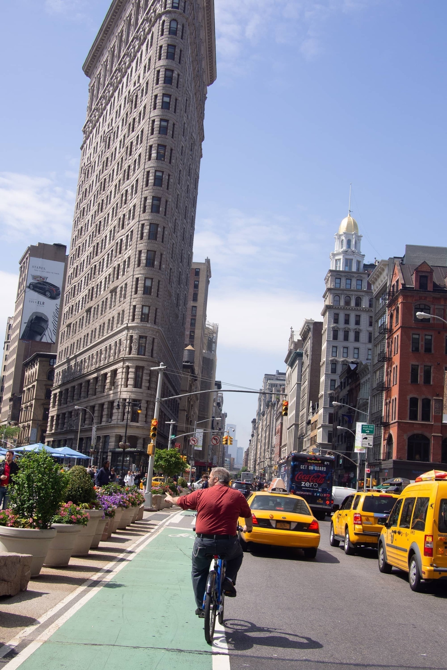 Man on bike points off to the left with Flatiron Building in the background - Olympus E-m5