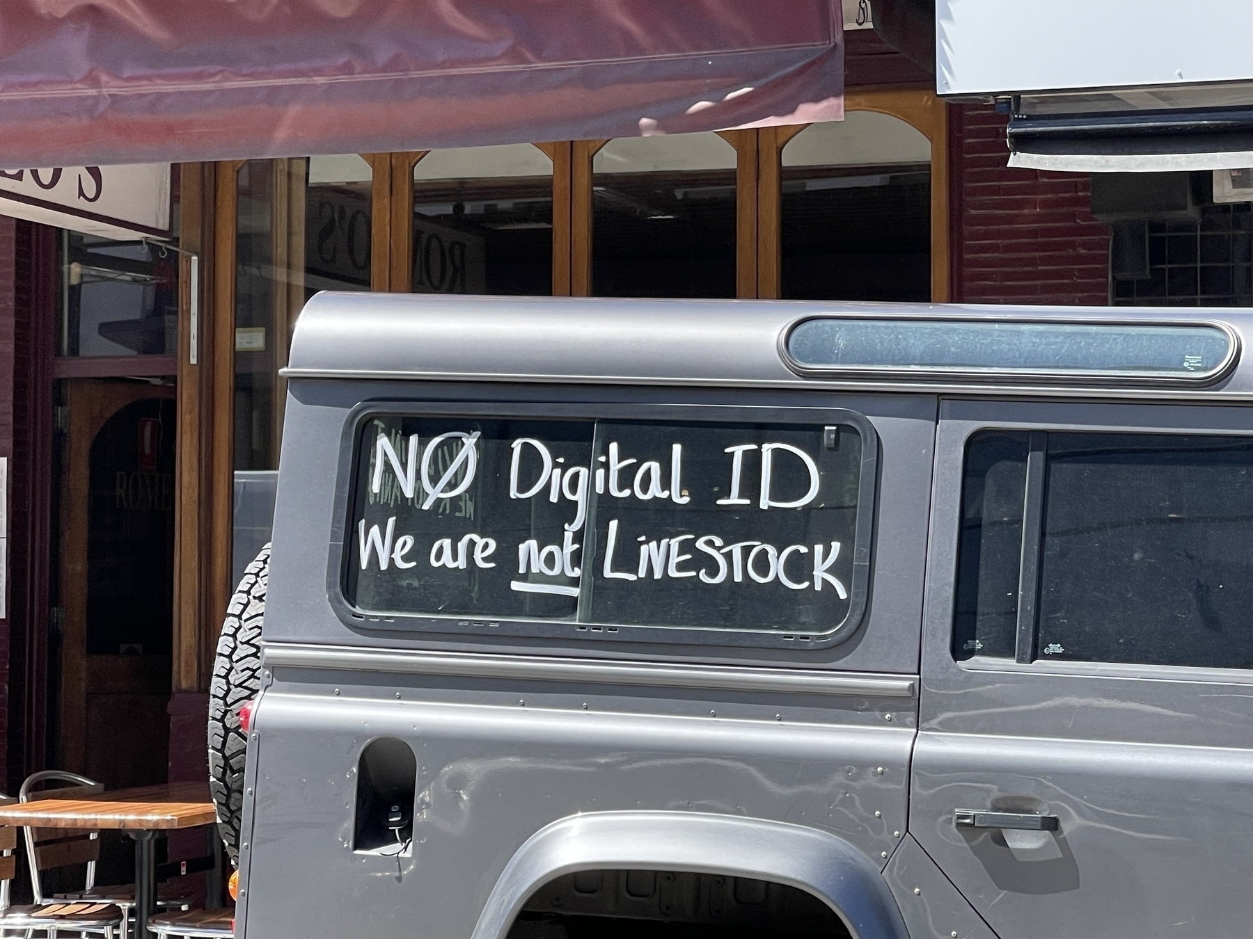 A hand painted sign on the side of a truck that reads “No digital ID. We are not livestock.”