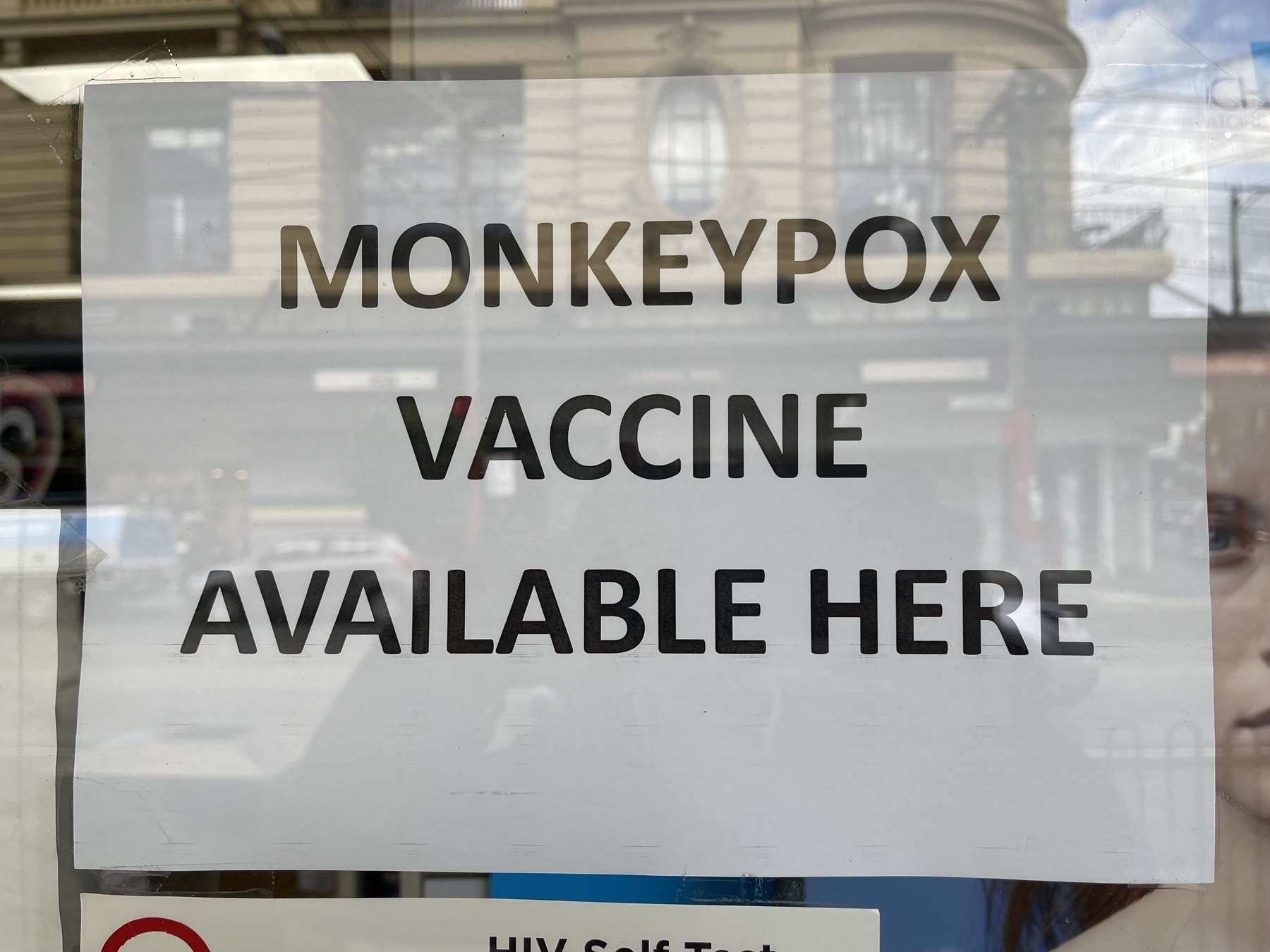 A sign in a pharmacy window that reads “ MONKEYPOX VACCINE AVAILABLE HERE.”