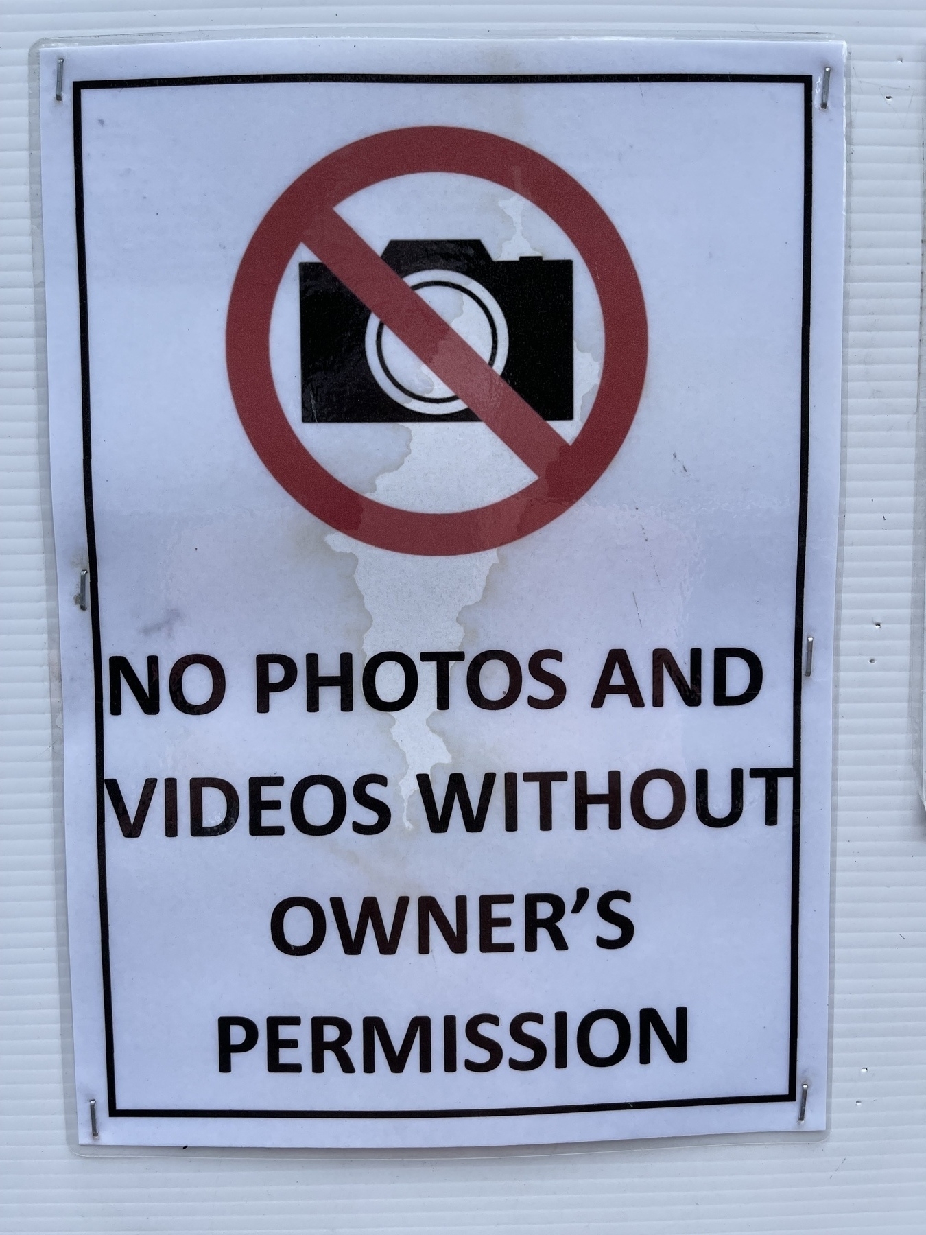A sign that reads “NO PHOTOS OR VIDEOS WITHOUT OWNERS PERMISSION.”