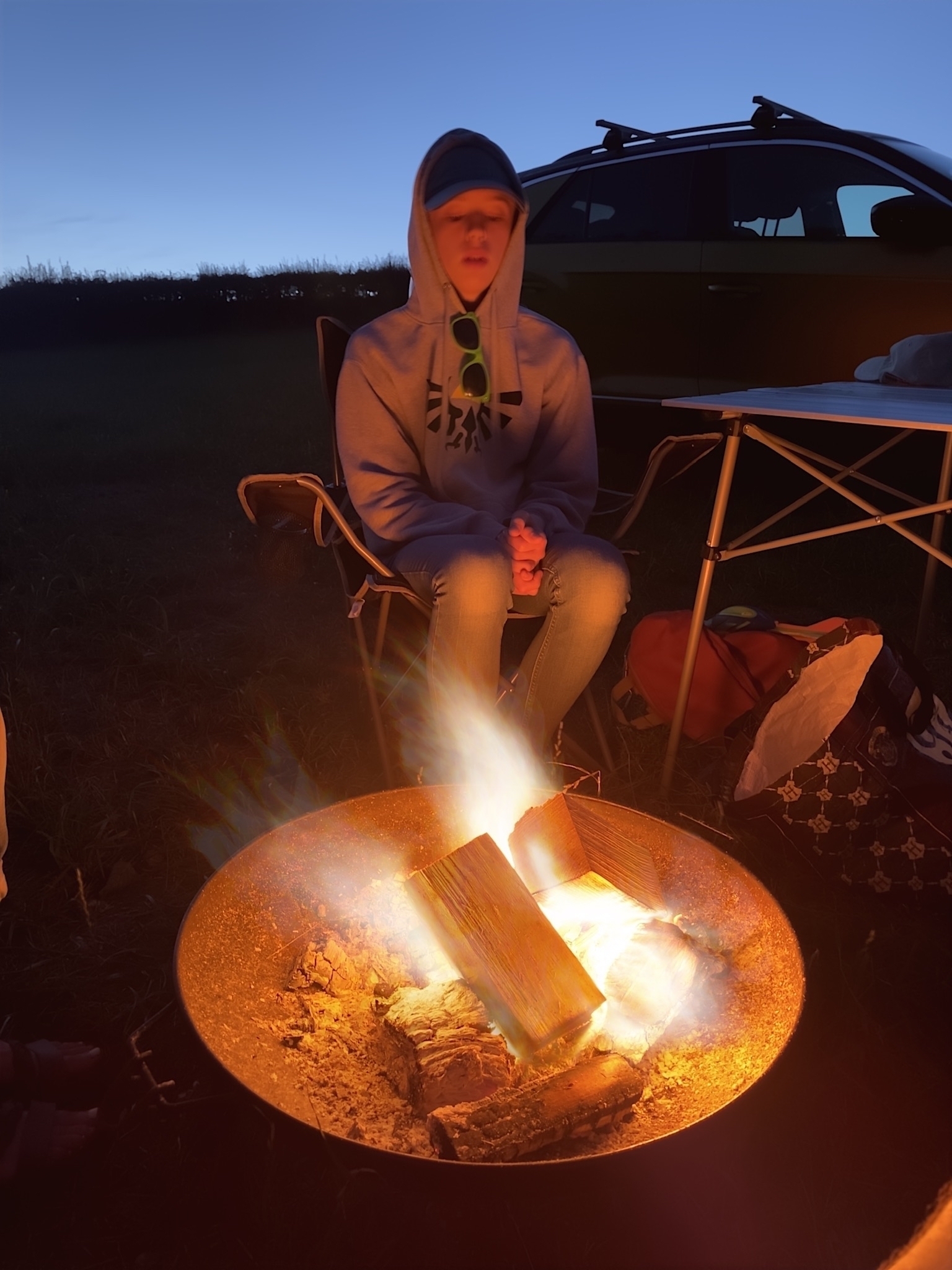 A long exposure of a campfire. My son in a hoodie is in the background as the light of the fire highlights his face