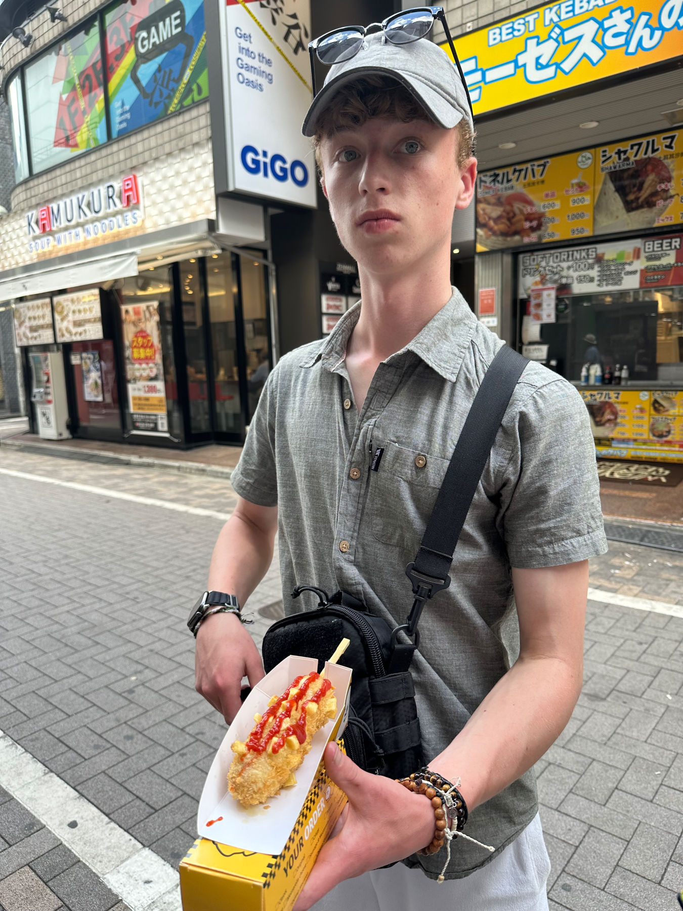 My son holding a Korean style hot dog on the streets of Shibuya
