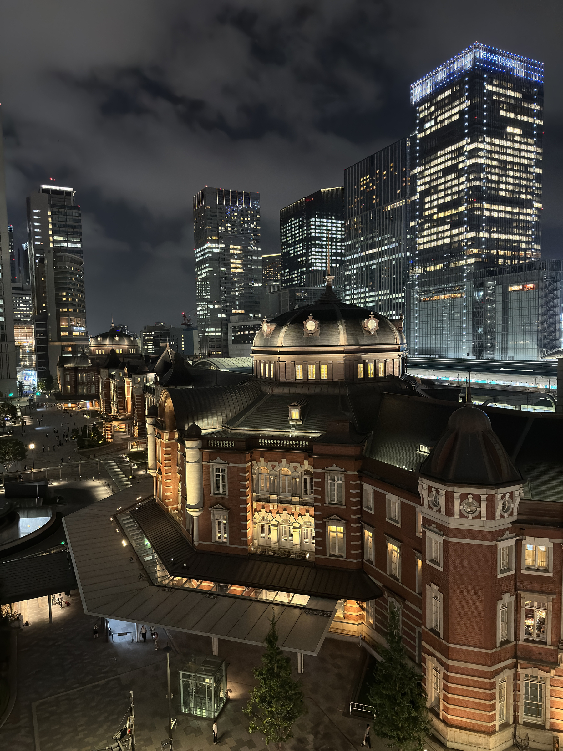 a view of the beautifully illuminated Tokyo station with the modern buildings and garden on display