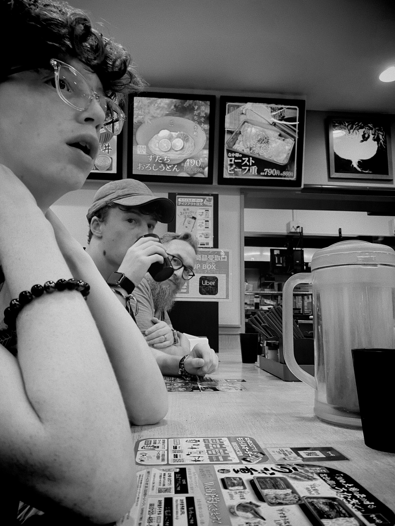 A black and white photo if us stood at the bar seating of a Japanese fast food restaurant 