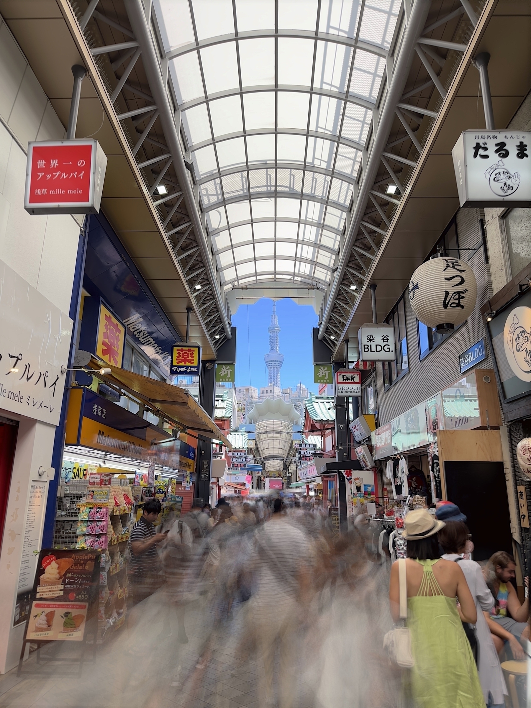 A long exposure of a japanese shopping street. people blur as they move with tokyo skytree in the distance