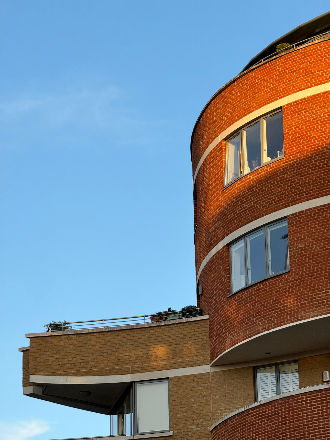 Golden hour light on the curved brick of a modern apartment