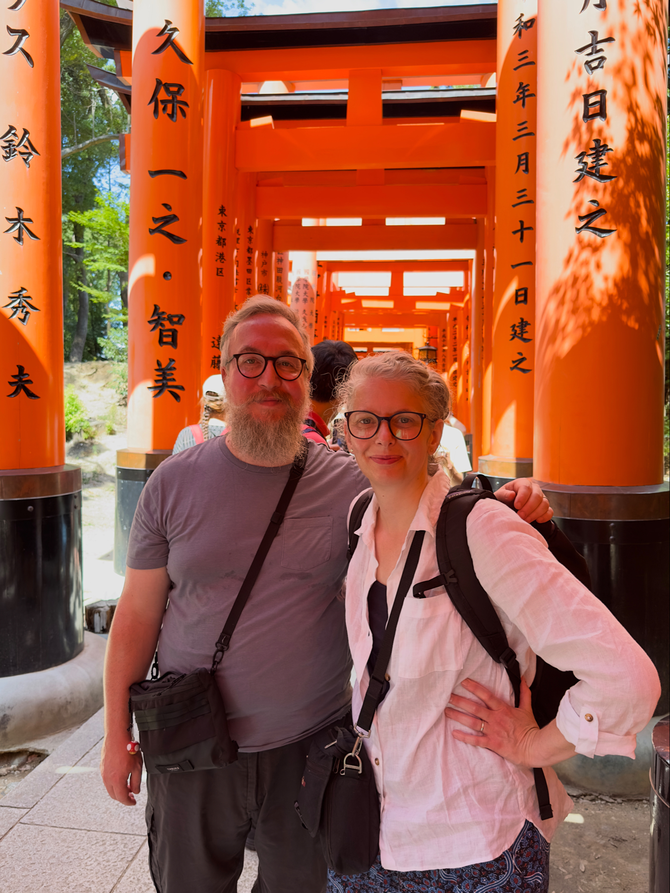 Myself and my Wife posing together under the red torii gates at Fushimi Inari Shrine in Kyoto, Japan.