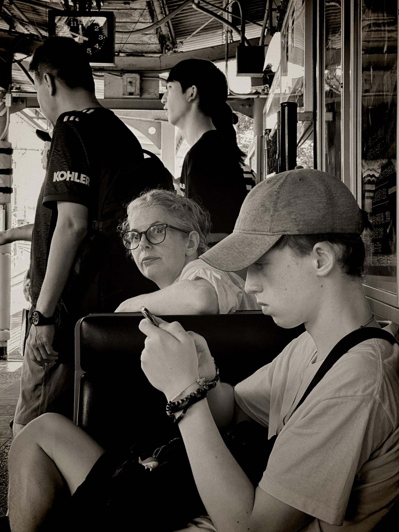 A black and white photo featuring my family waiting for the train a the ration. Other passengers stand nearby, facing away.