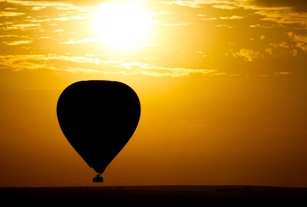 Silhouette of a balloon in front of an orange sunrise. 