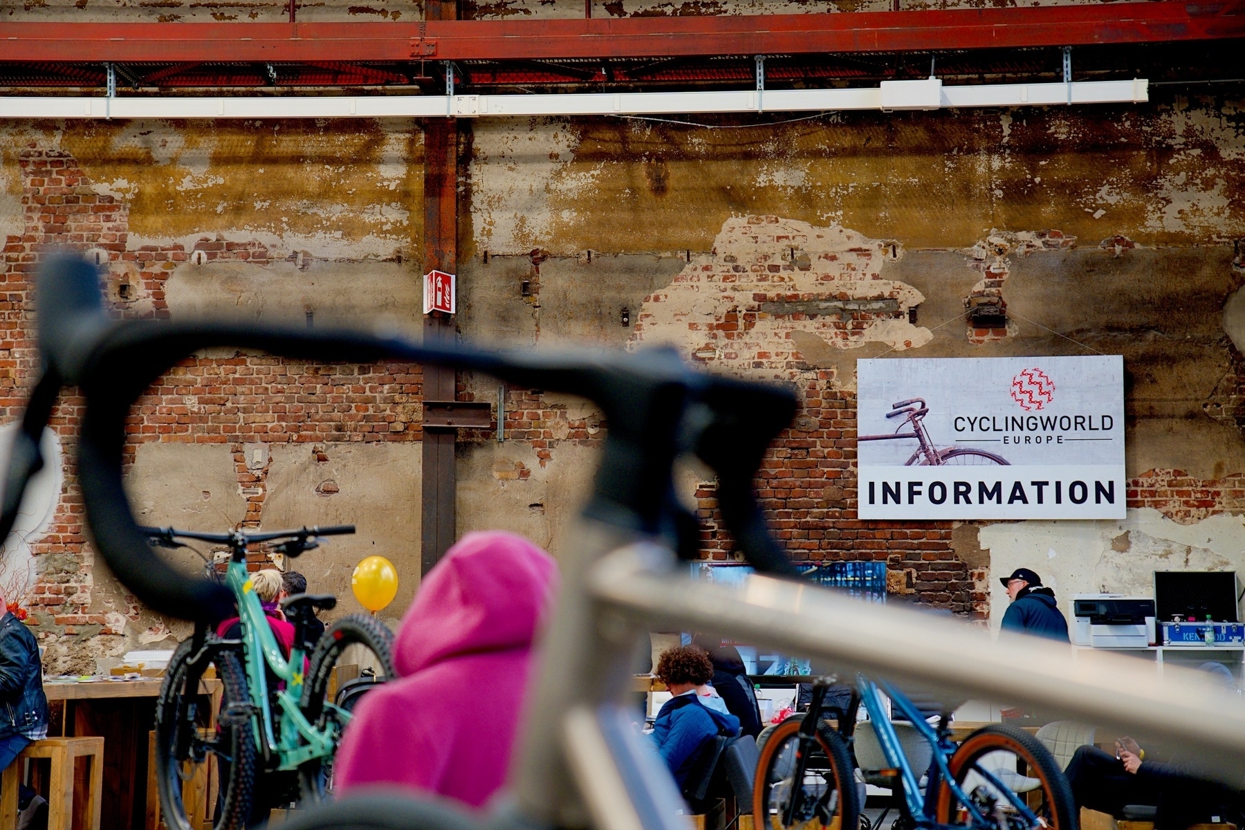 A Cyclingworld information sign on a brick wall. A bicycle in the foreground.