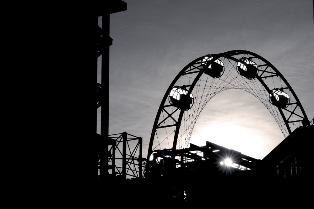 Black and white image of a ferris wheel against the sun.