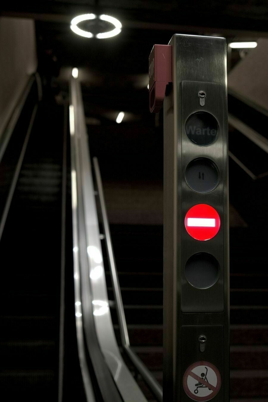 A escalator, a red stop sign illuminated.