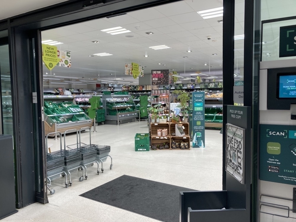Waitrose entrance showing green shelves and lack of people shopping