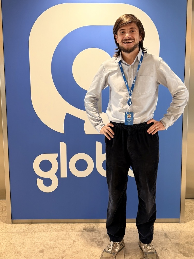 Me standing in front of elevators with global logo behind