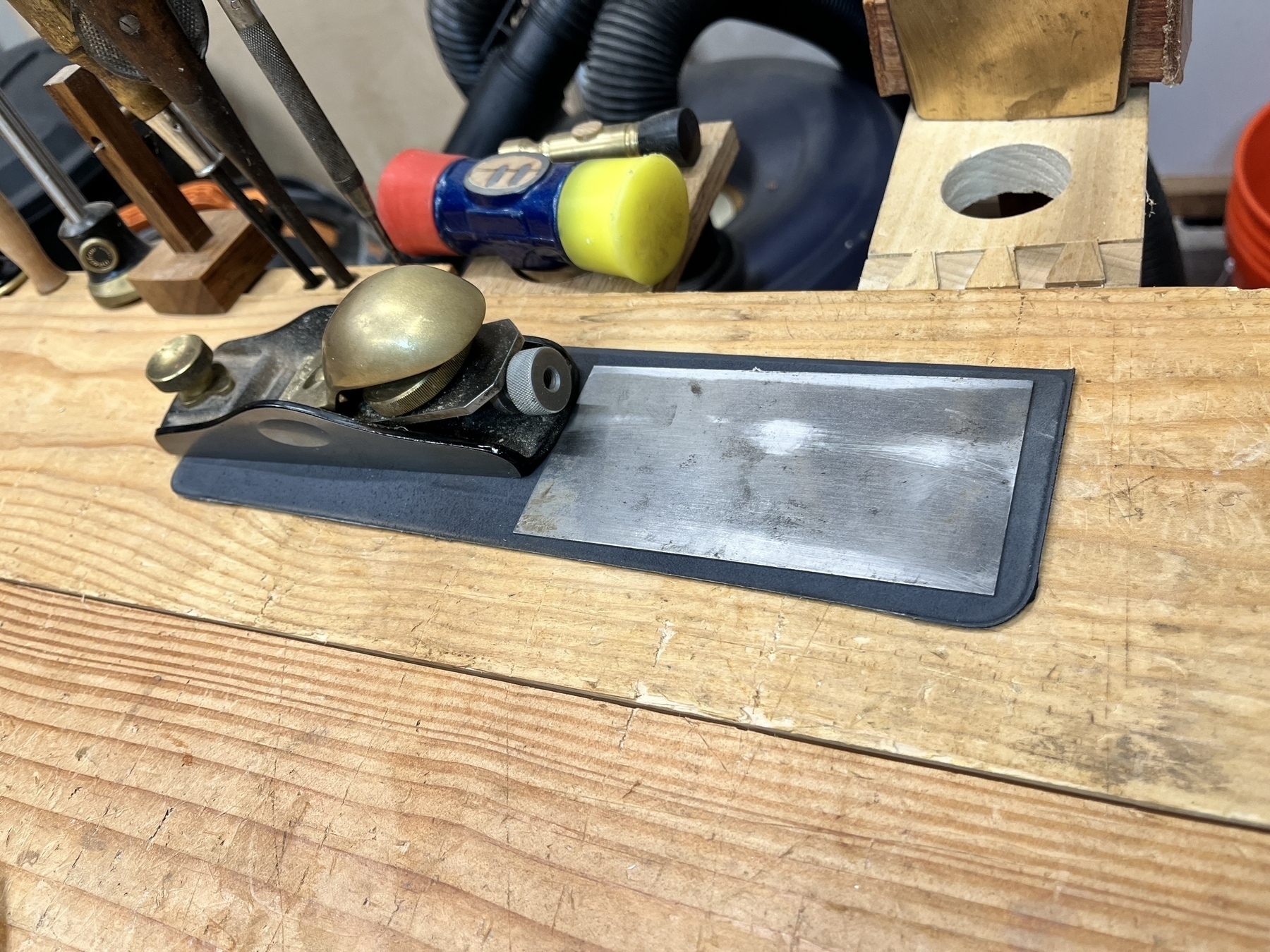 Block plane and card scraper on workbench, held on magnetic bit of old iPad Folio keyboard case cut out.