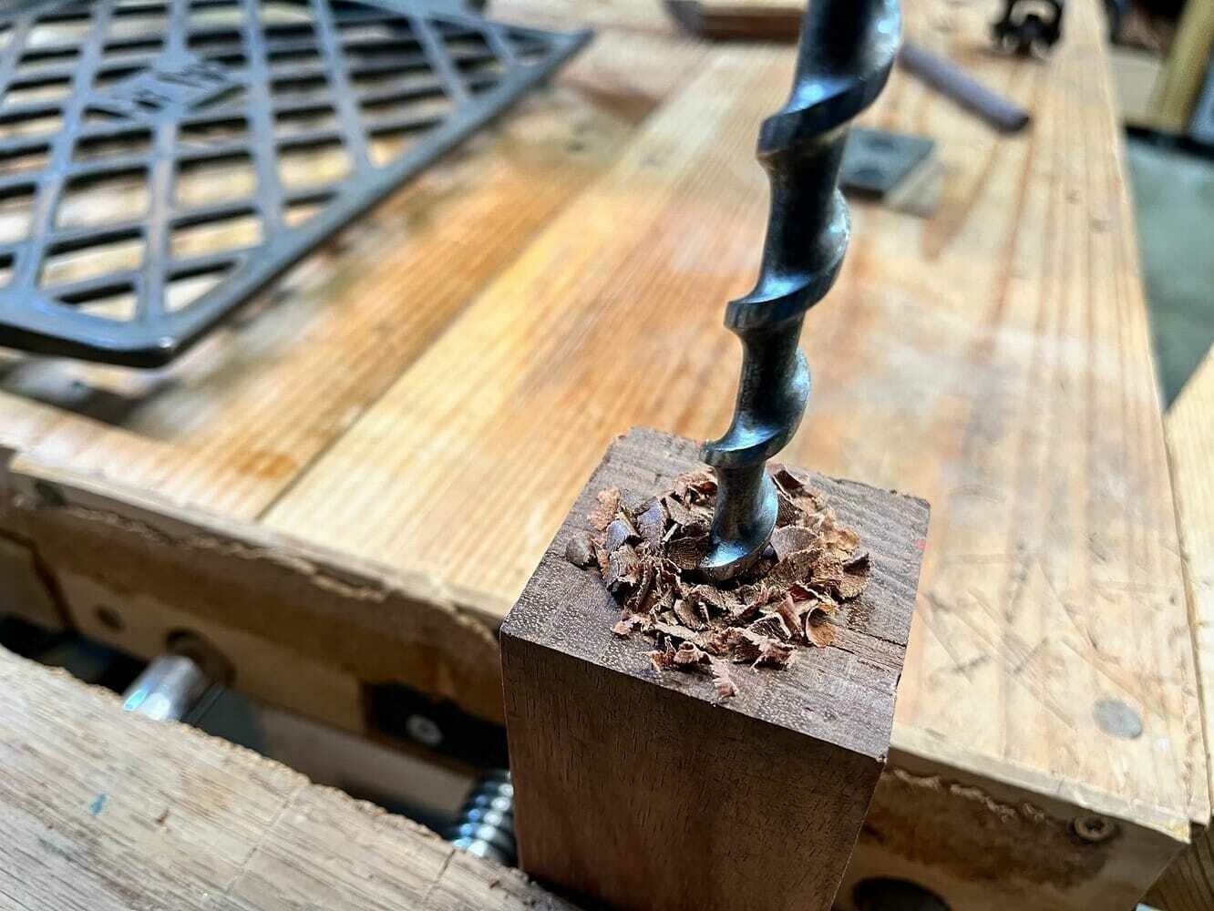 close-up of using hand drill to drill holes into ends of bubinga base.