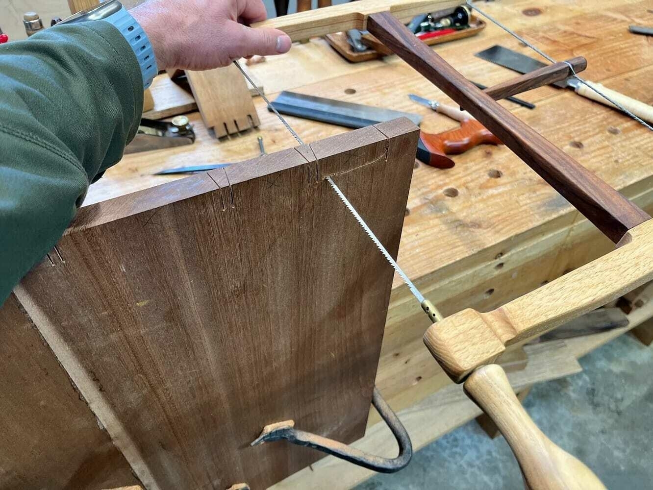 Cutting dovetail waste out with bow saw.