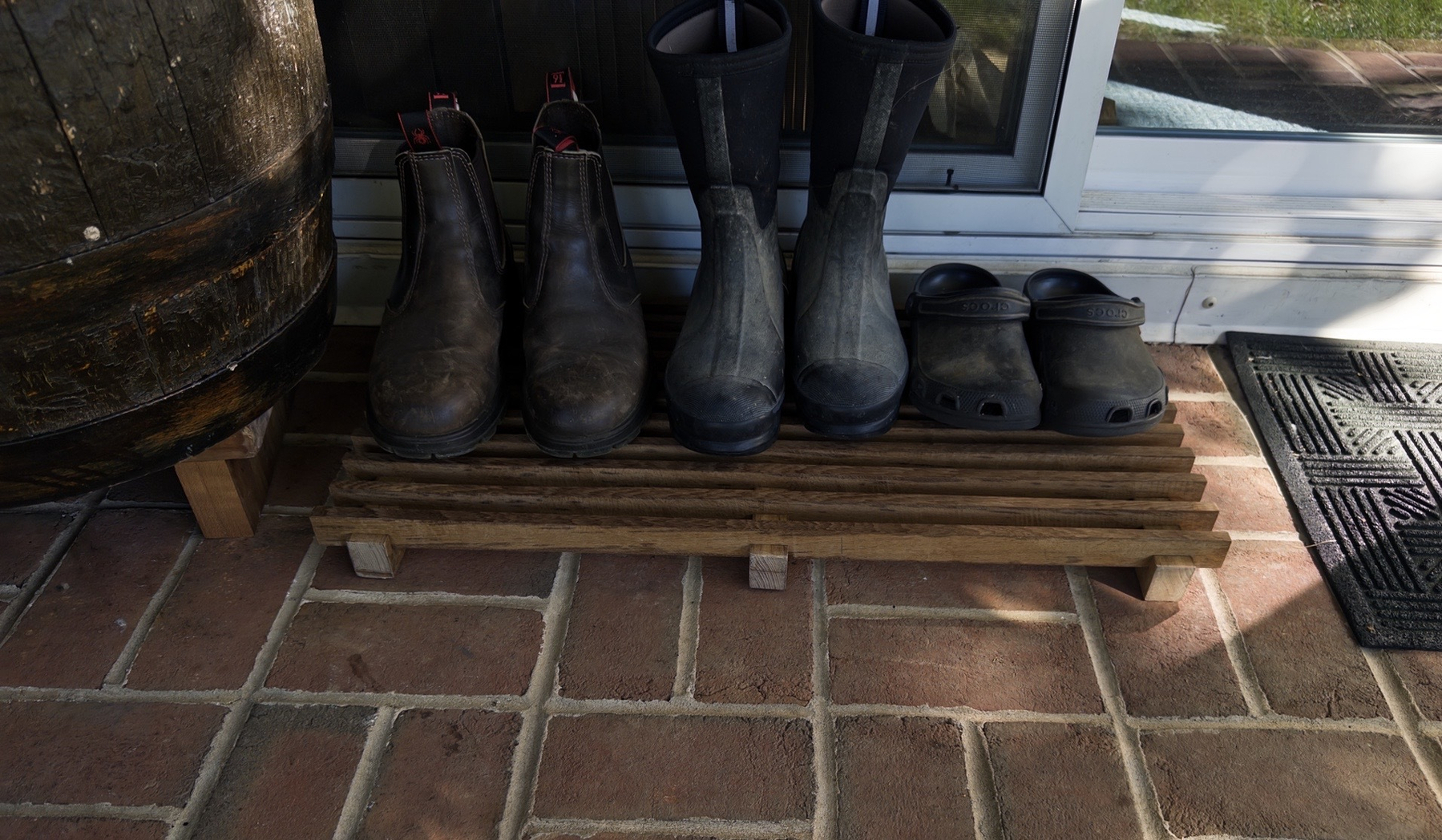 teak-boot-rack.jpeg Teak boot rack on a porch with boots and sandals on it