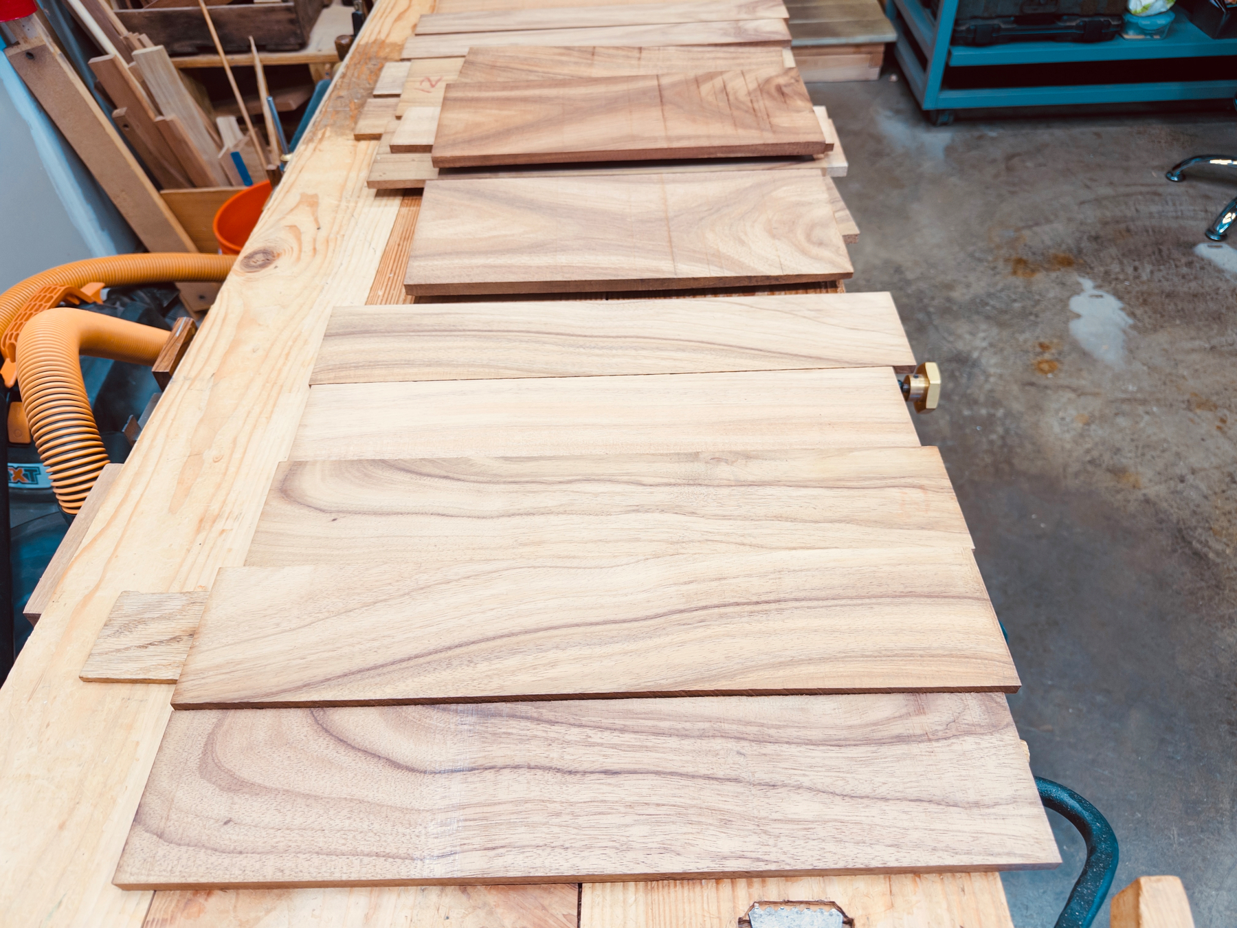 Several wooden boards are laid out on a workbench in a workshop setting.
