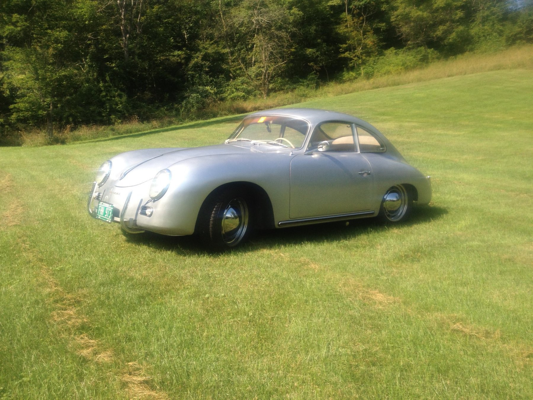 Chrome '60s era Porsche in a sunny field.
