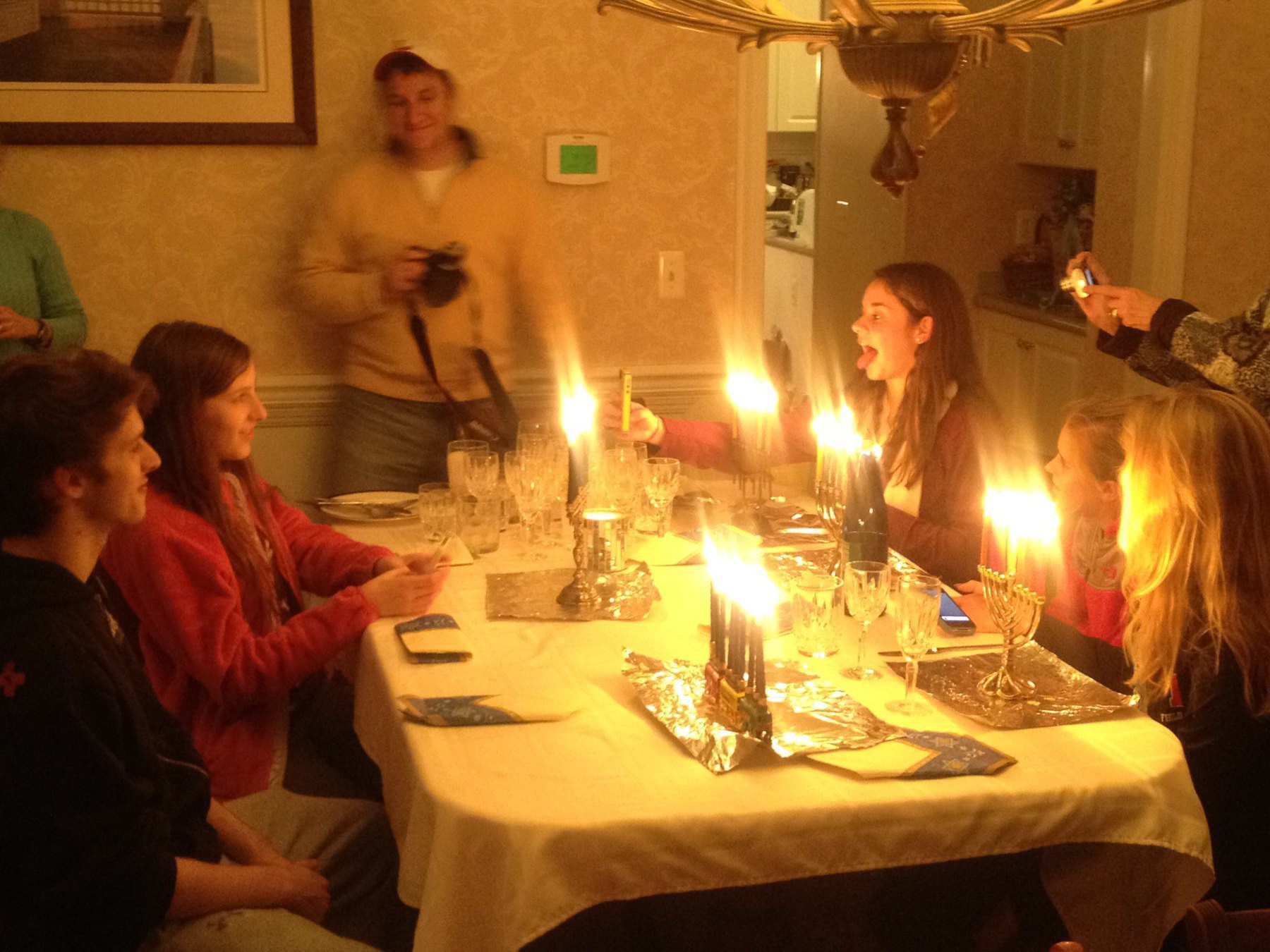 Family at a dining table with a lot of menorahs.